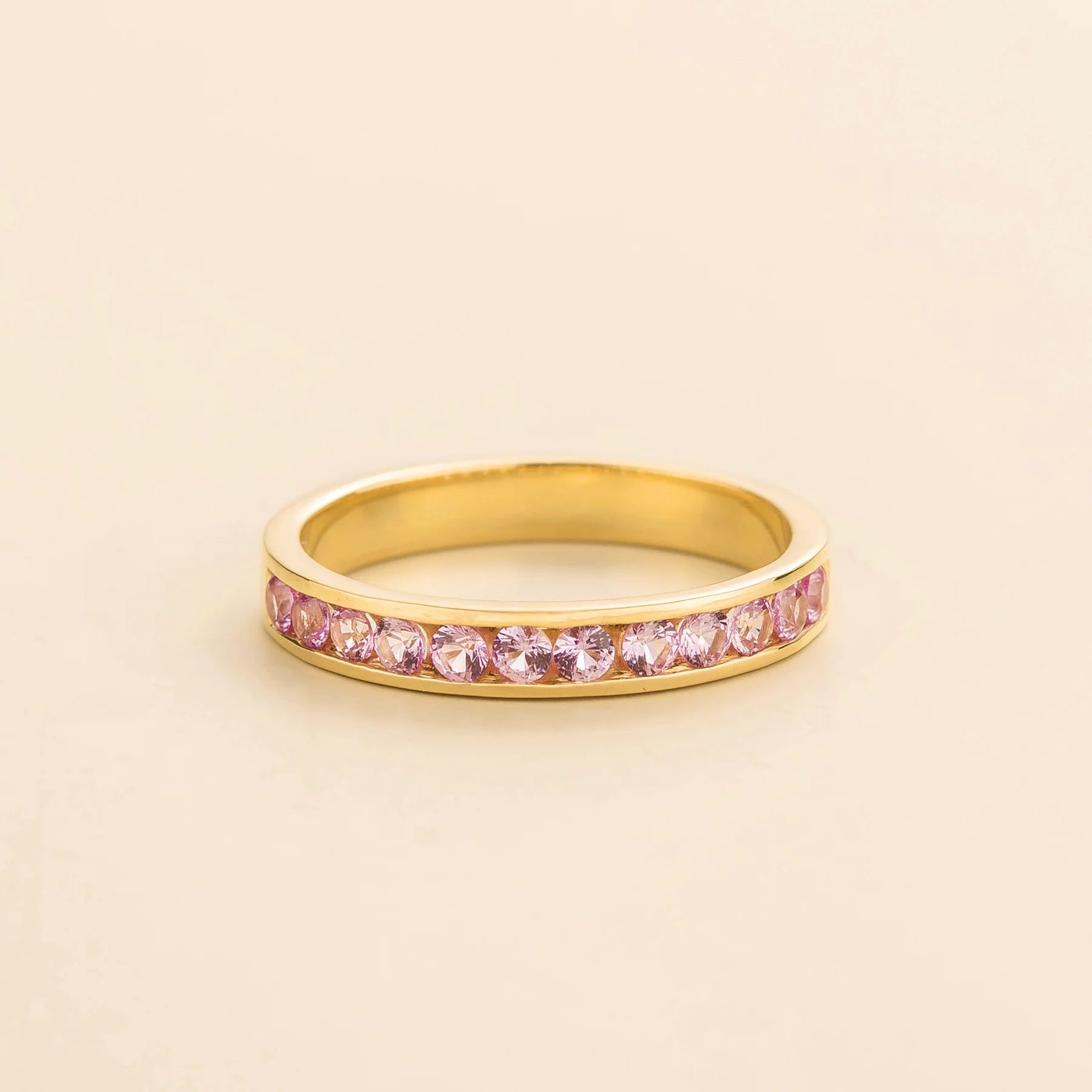 Juvetti yellow gold channel-set band featuring round lab-grown pink sapphires.