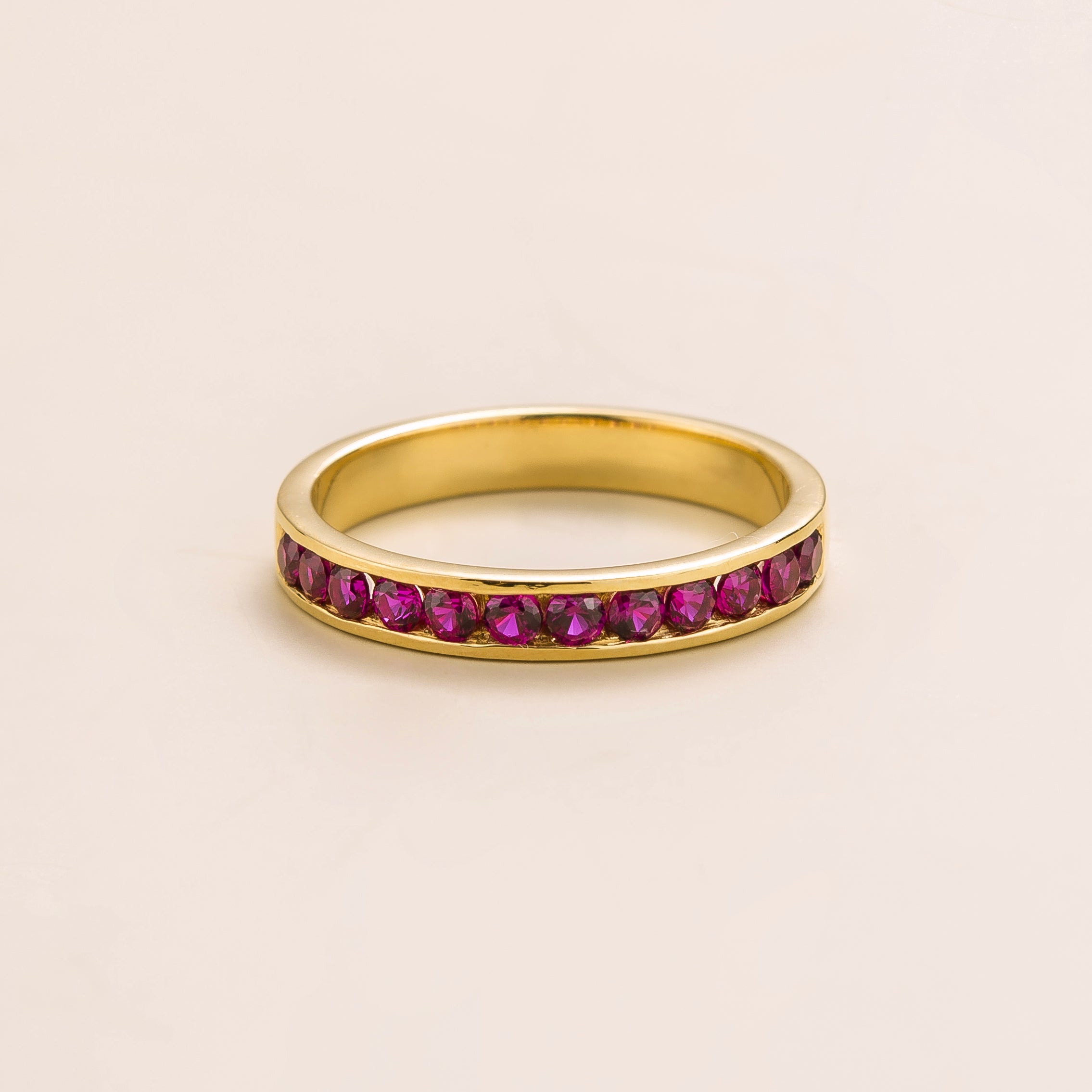 Juvetti yellow gold channel-set band featuring round lab-grown ruby gemstones.