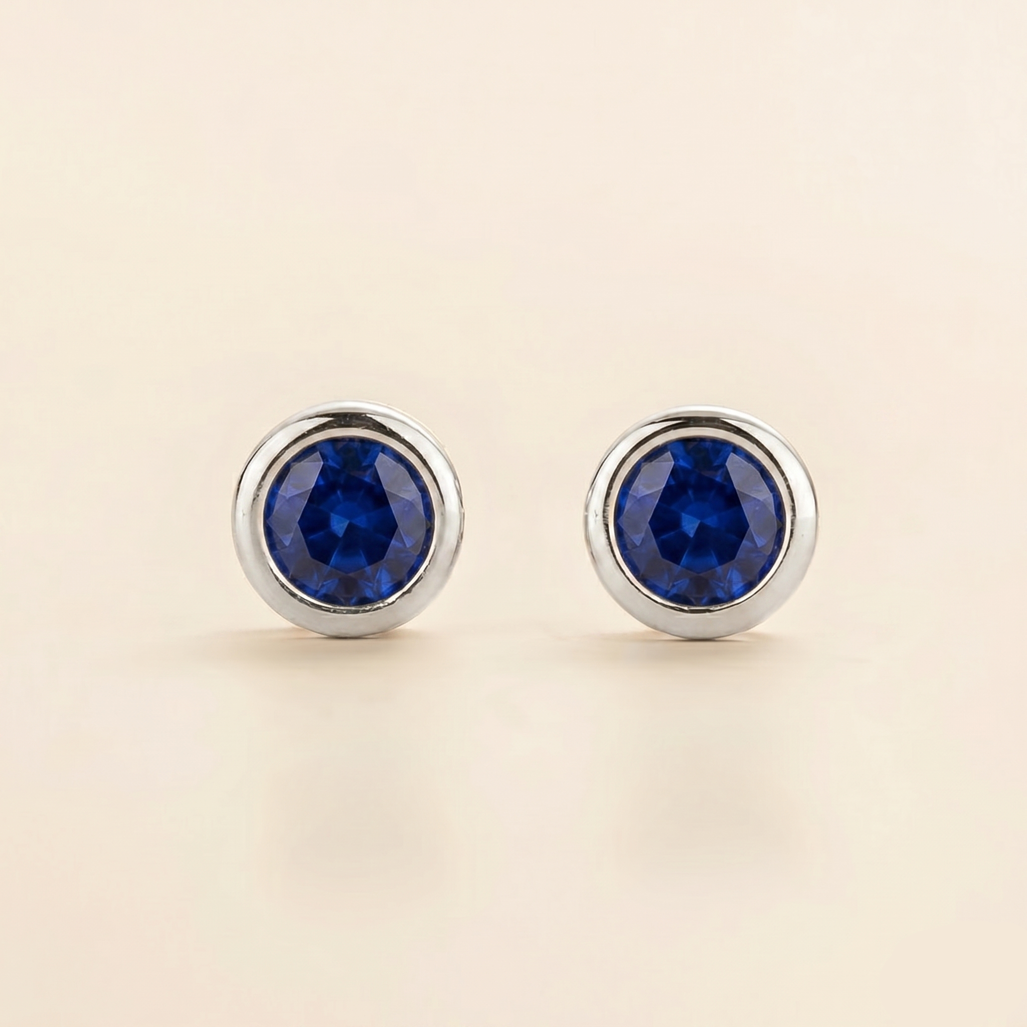 Round bezel-set lab-grown blue sapphire Margo earrings in white gold | Juvetti London