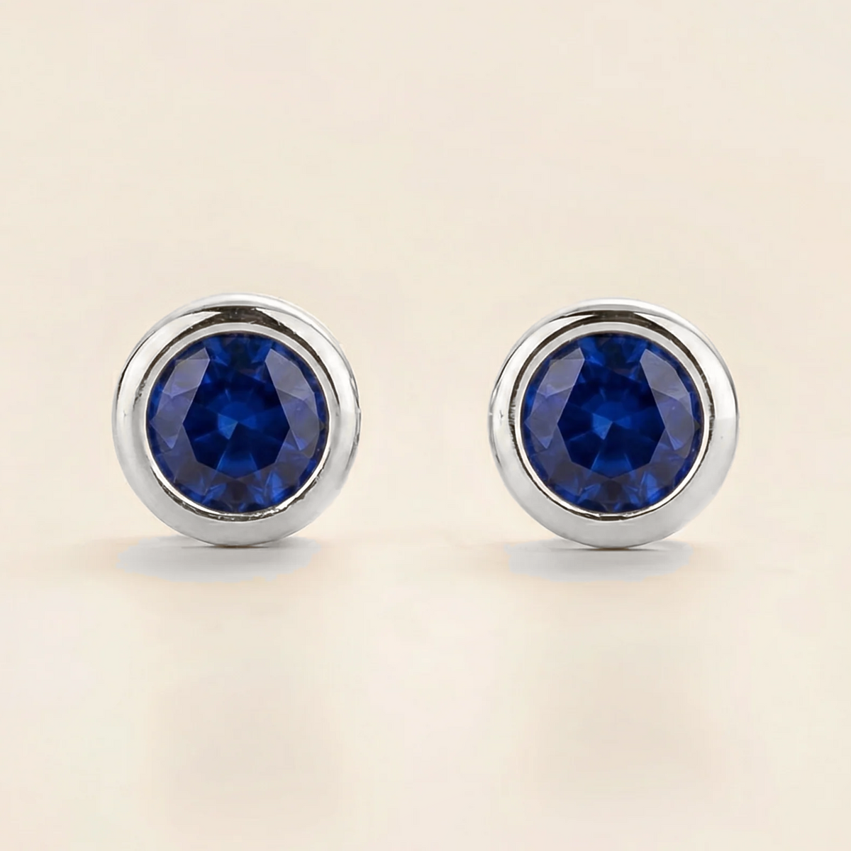 Round bezel-set lab-grown blue sapphire Margo earrings in white gold | Juvetti London