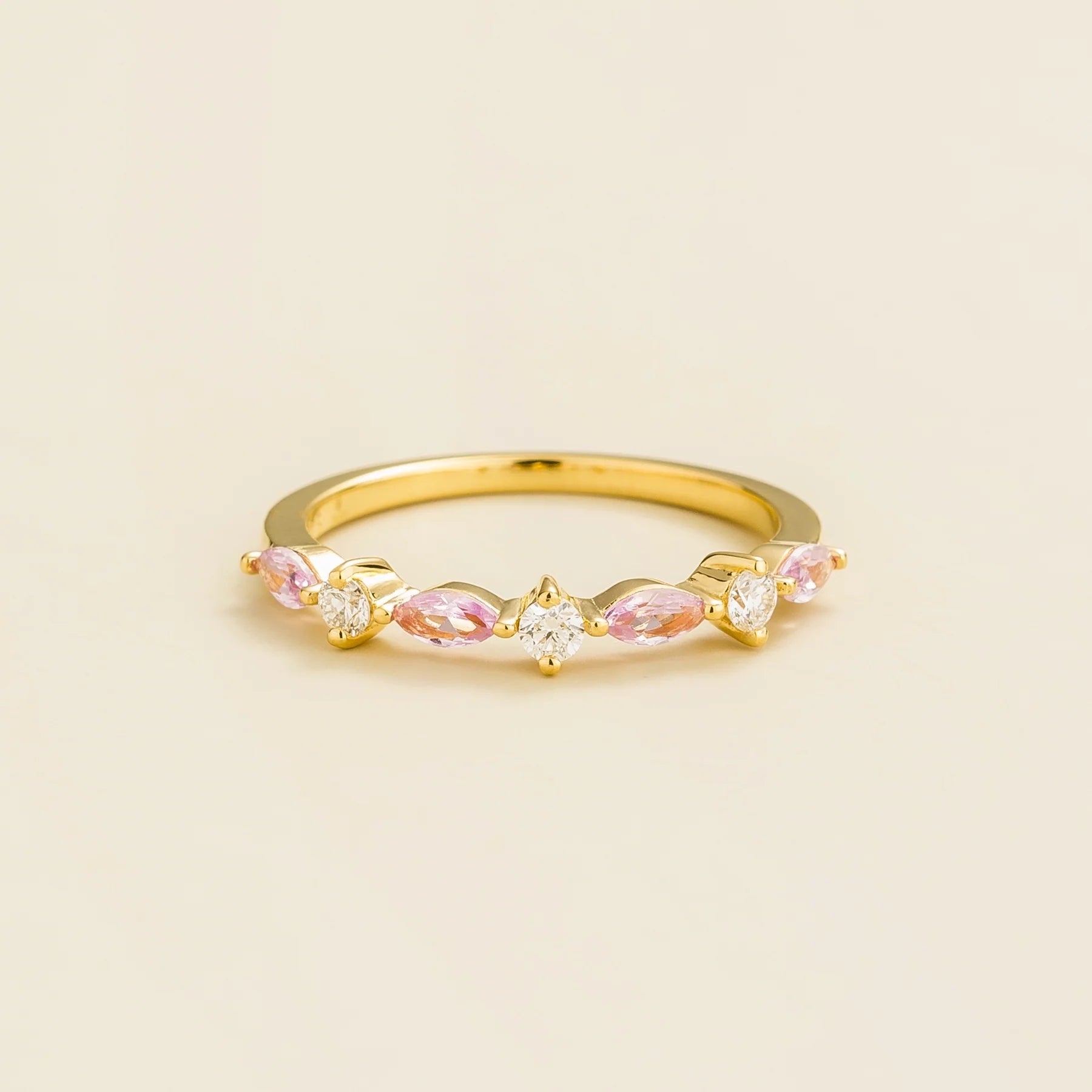 A gold band ring set with marquise cut pink sapphires and round diamonds.