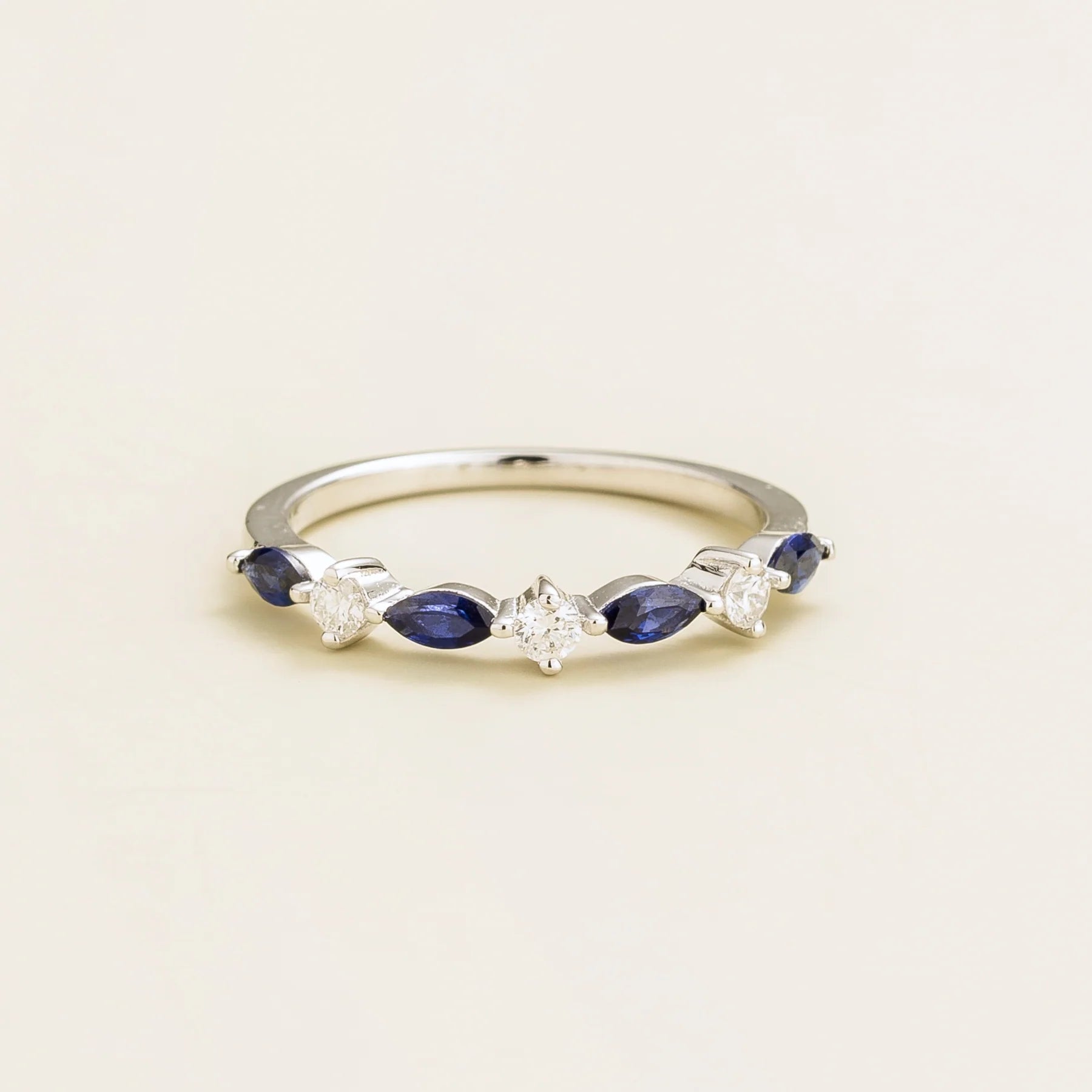 A white gold band ring set with marquise cut blue sapphires and round diamonds.