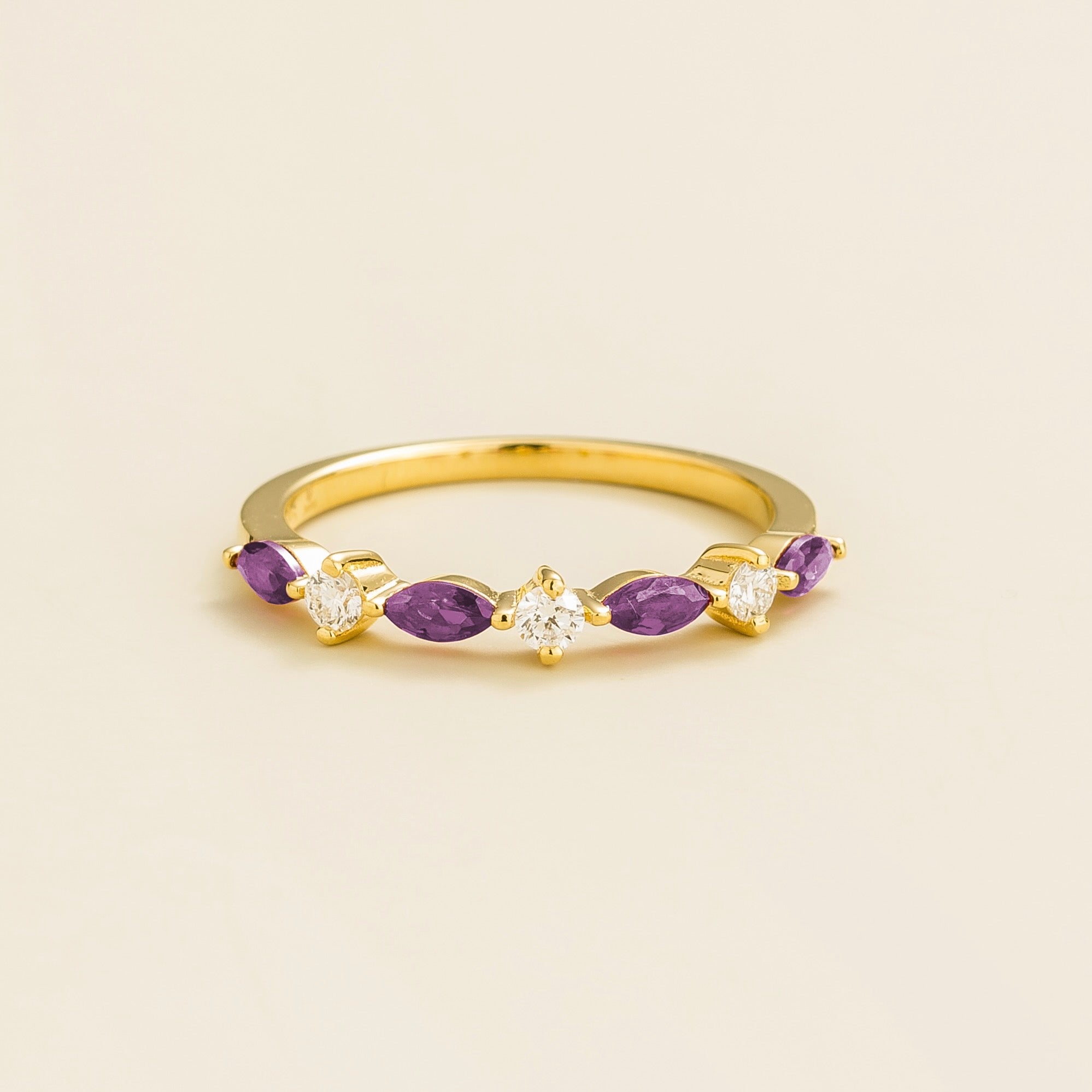 A gold band ring with marquise cut purple sapphires and round diamonds set on it.