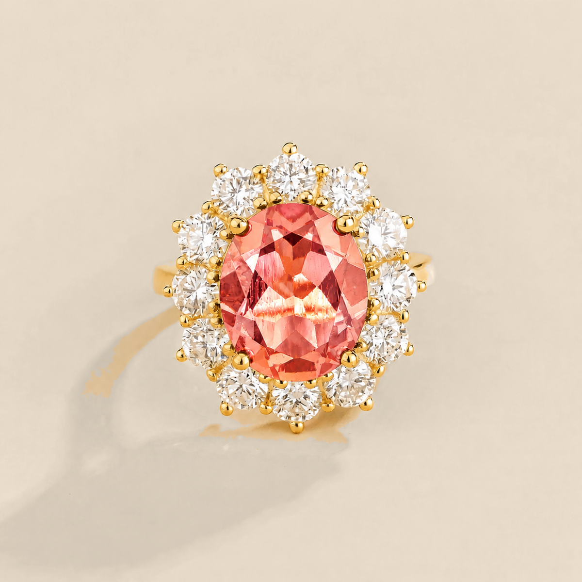 Juvetti yellow gold halo ring featuring an oval lab-grown padparadscha sapphire surrounded by round lab-grown diamonds.