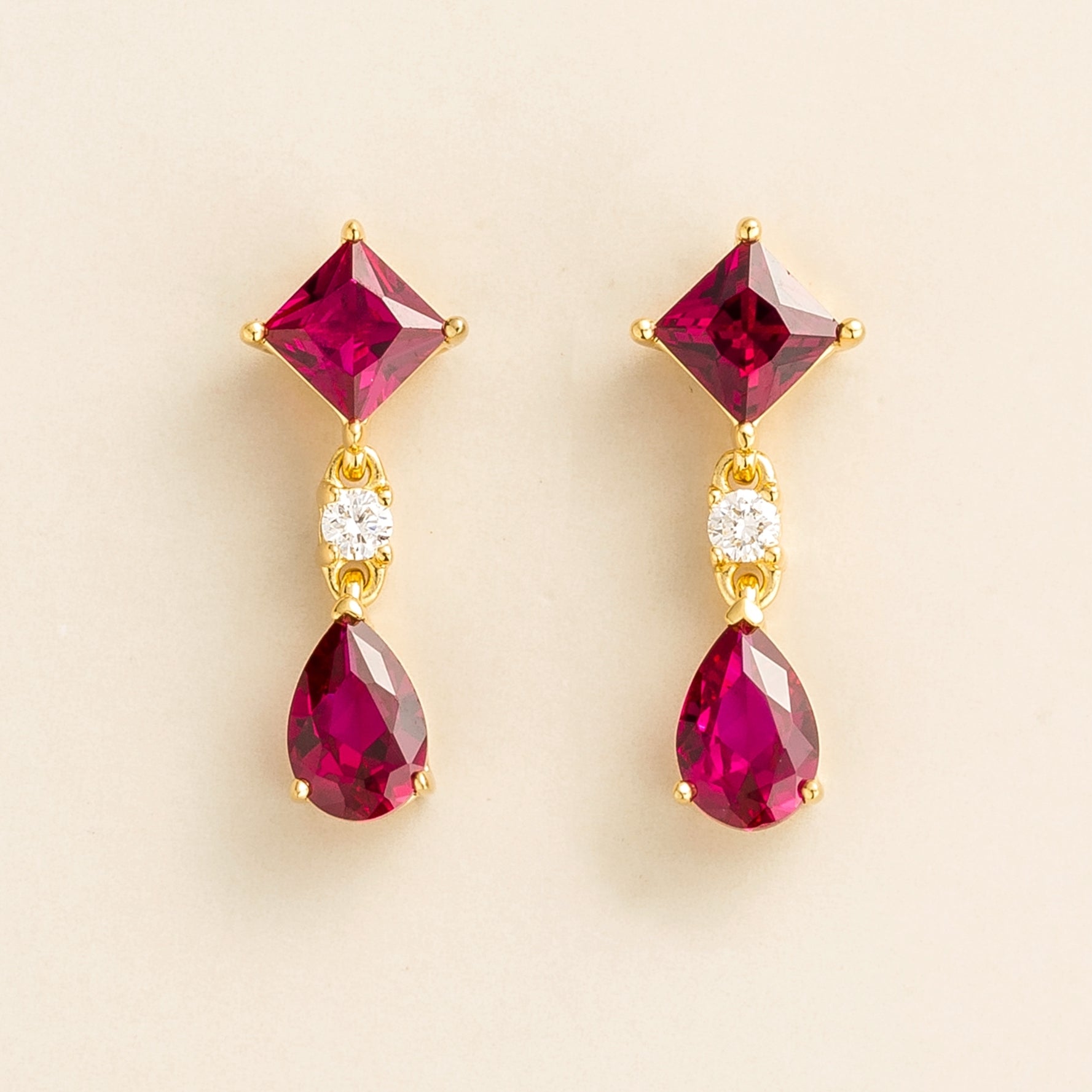 A pair of Ori gold drop earrings featuring princess cut rubies and round cut diamonds over pear cut rubies.