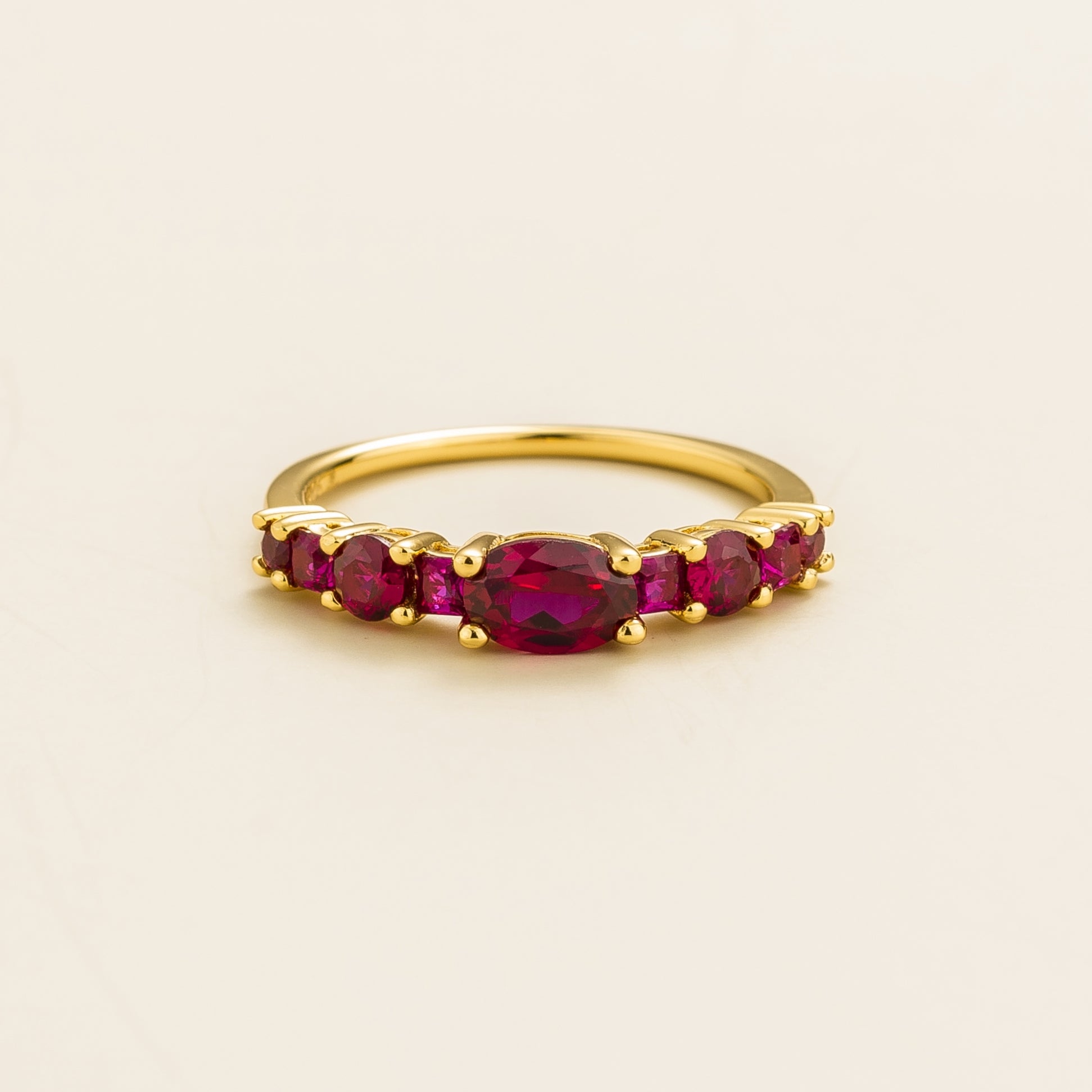 Juvetti yellow gold ring featuring lab-grown rubies in oval, princess, and round cuts for a timeless half-eternity look.