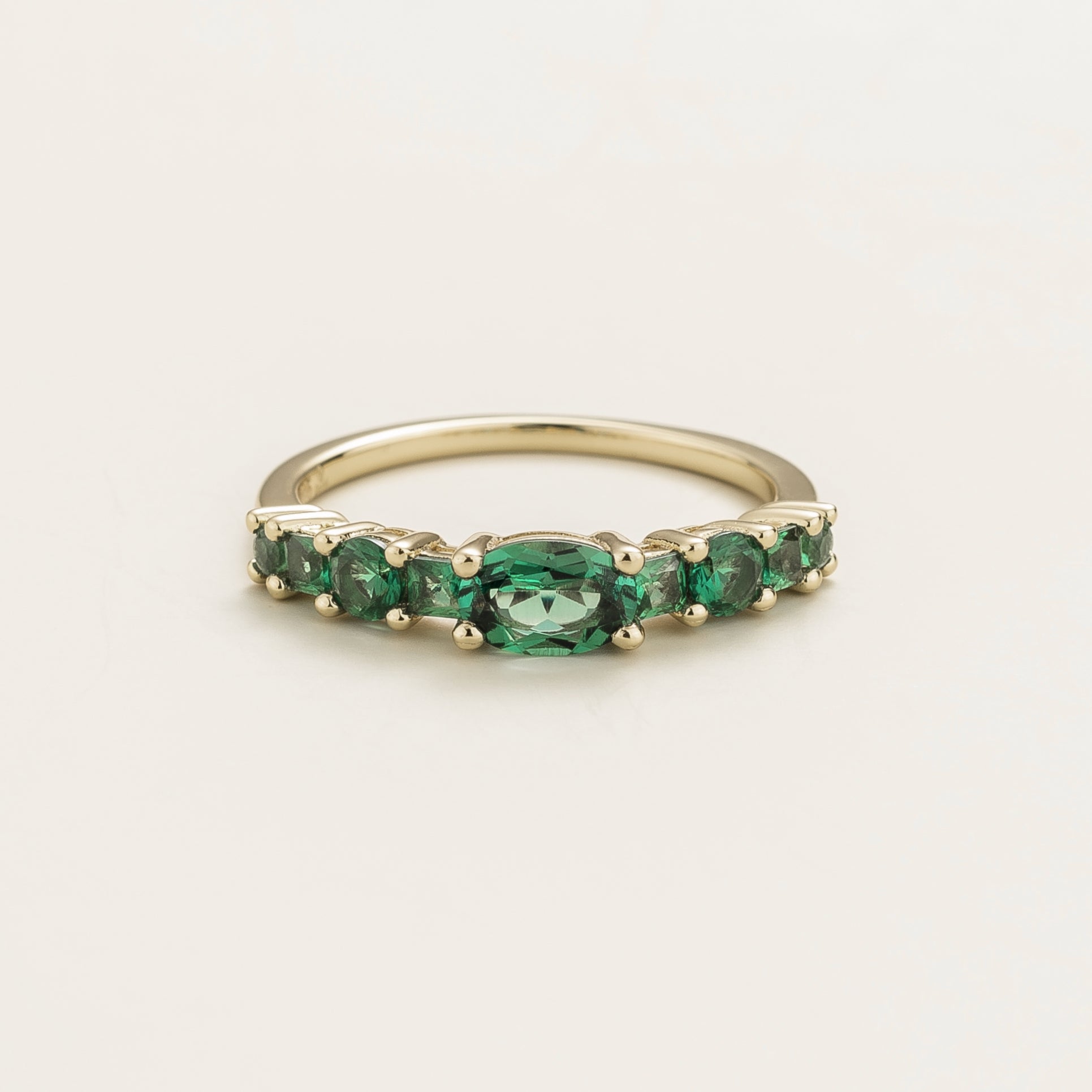 Juvetti white gold ring featuring lab-grown emeralds in oval, princess, and round cuts for a timeless half-eternity look.