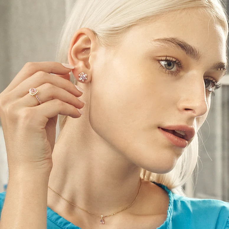 A model wearing hexagon Melba earrings, triangle Diana ring and pear drop Ori necklace set with lab grown diamond and pink sapphire gem stones. Pink Sapphire Earrings with Diamond are the perfect online jewellery gift any man can buy.