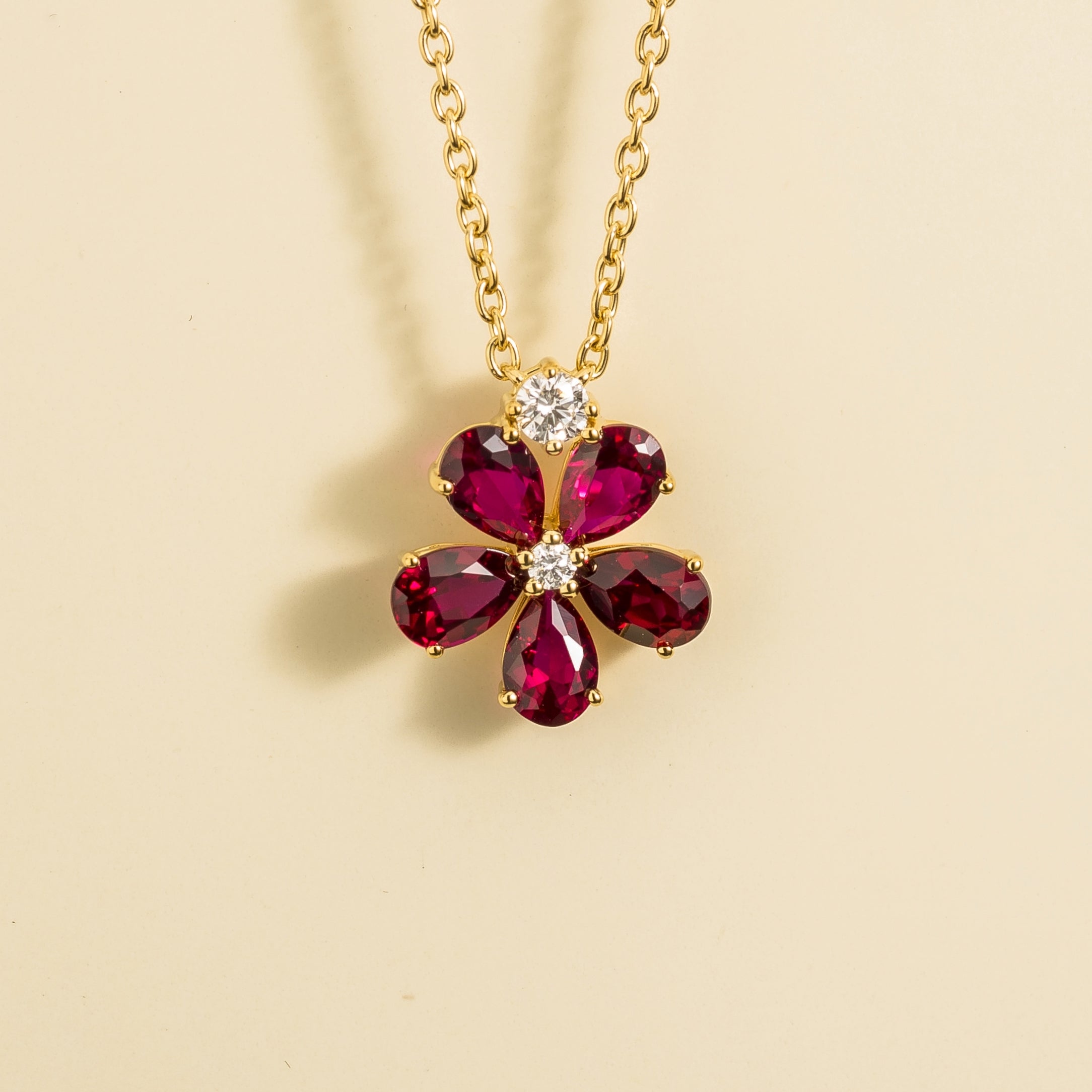 A gold necklace with a florea flower pendant set with rubies and diamonds by Juvetti London