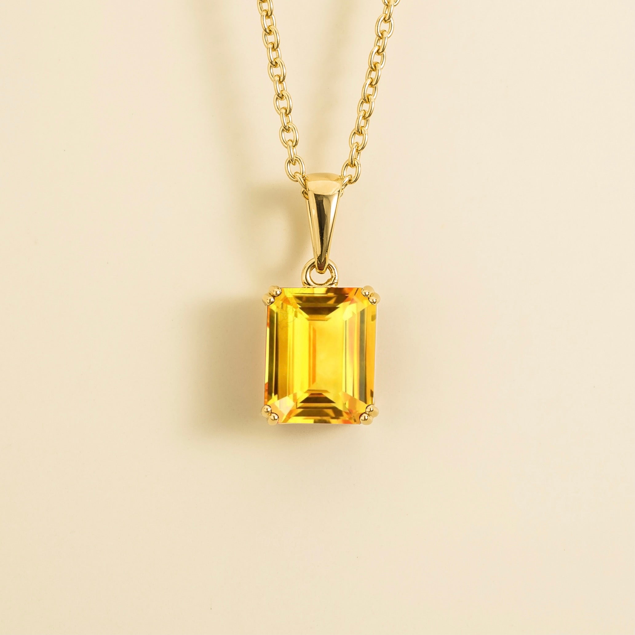 A gold pendant necklace with a yellow sapphire center stone, emerald cut design. :London jewellery store