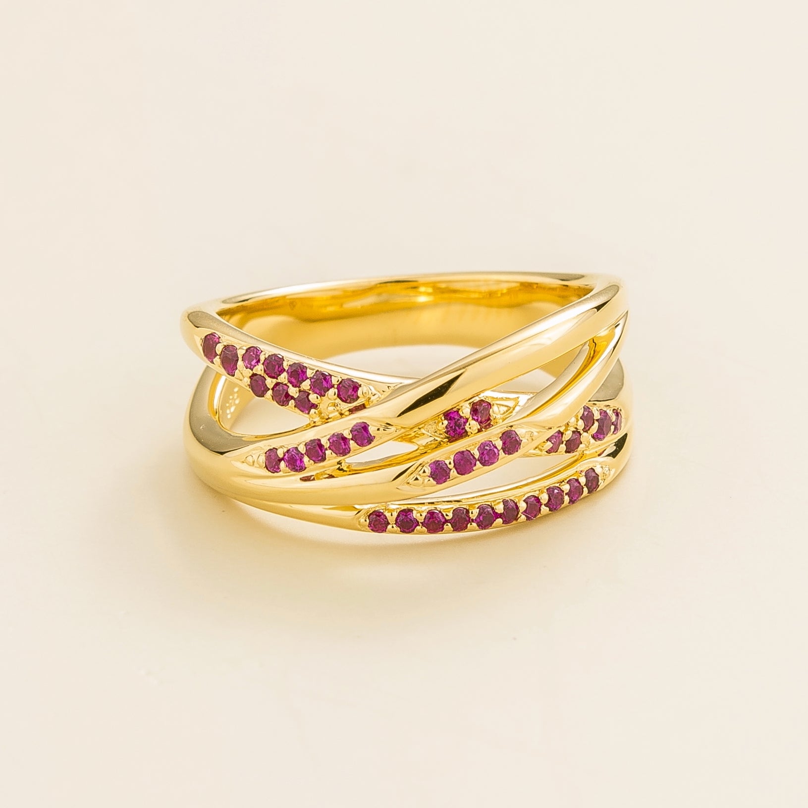 Juvetti yellow gold crossover ring set with round lab-grown ruby gemstones.