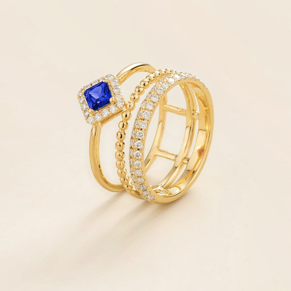 Amici triple-band stacking ring in gold, princess-cut lab-grown blue sapphire in a diamond halo with beaded and pavé bands, side view | Juvetti London