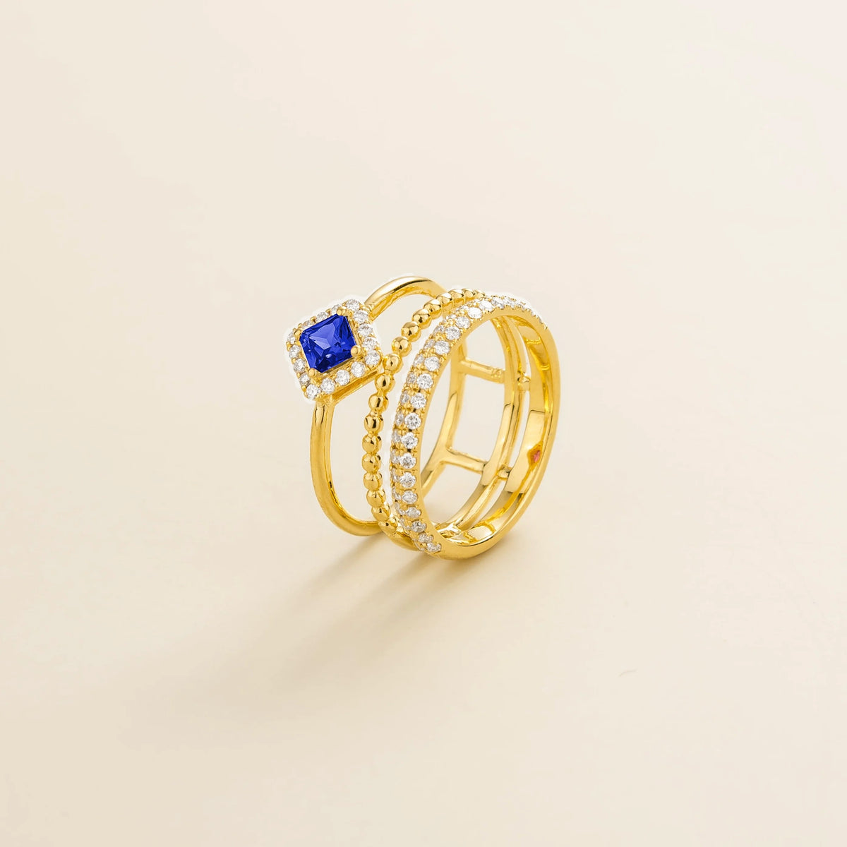 Amici triple-band stacking ring in gold, princess-cut lab-grown blue sapphire in a diamond halo with beaded and pavé bands, side view | Juvetti London