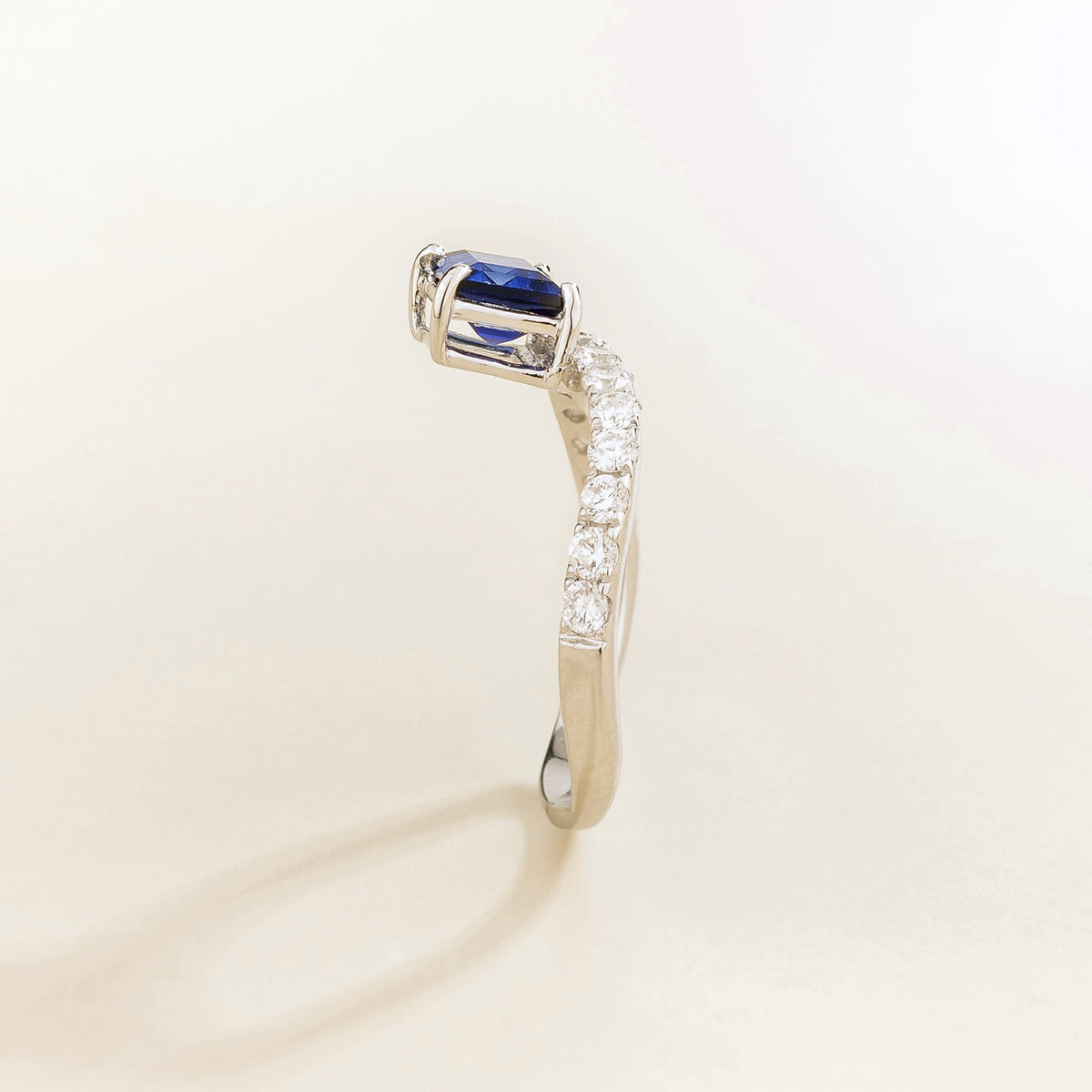 Luno blue sapphire emerald-cut ring with diamond pavé in white gold, lab-grown sapphire set east-west, profile view | Juvetti London