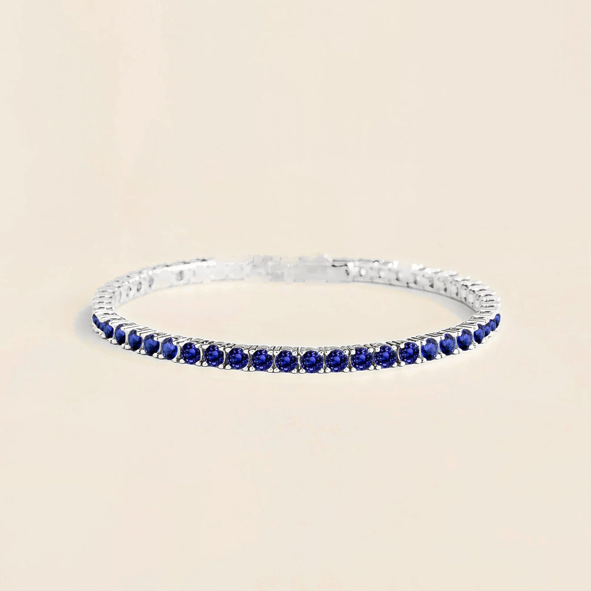 A white gold tennis bracelet set with round blue sapphire gemstones.