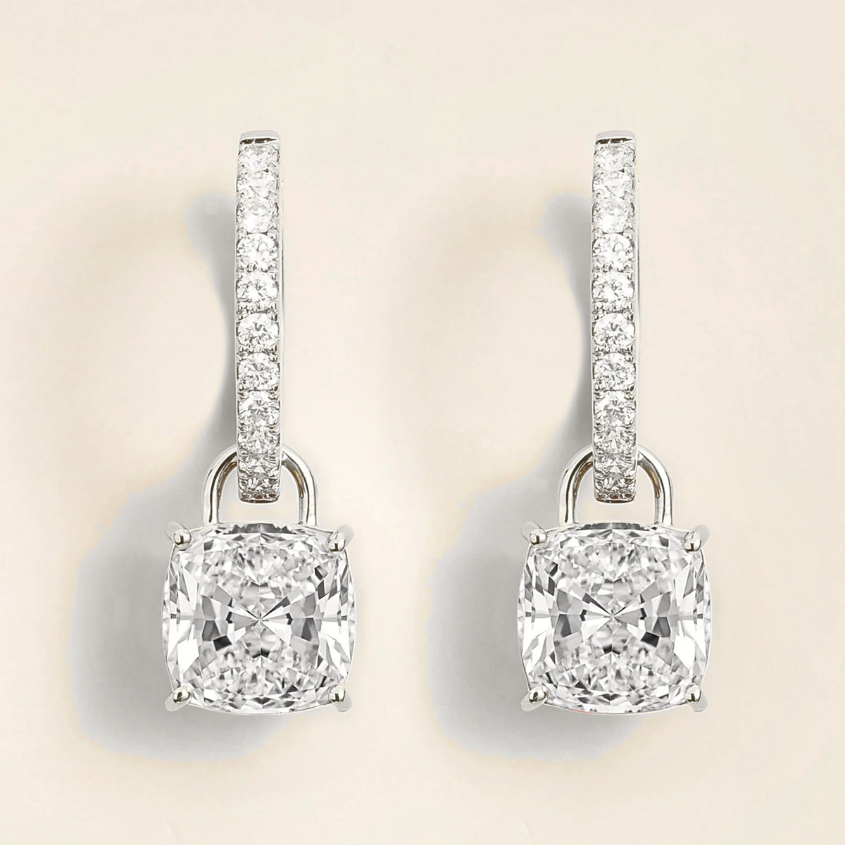 A pair of white gold drop earrings with cushion cut diamonds and smaller hoop design accents