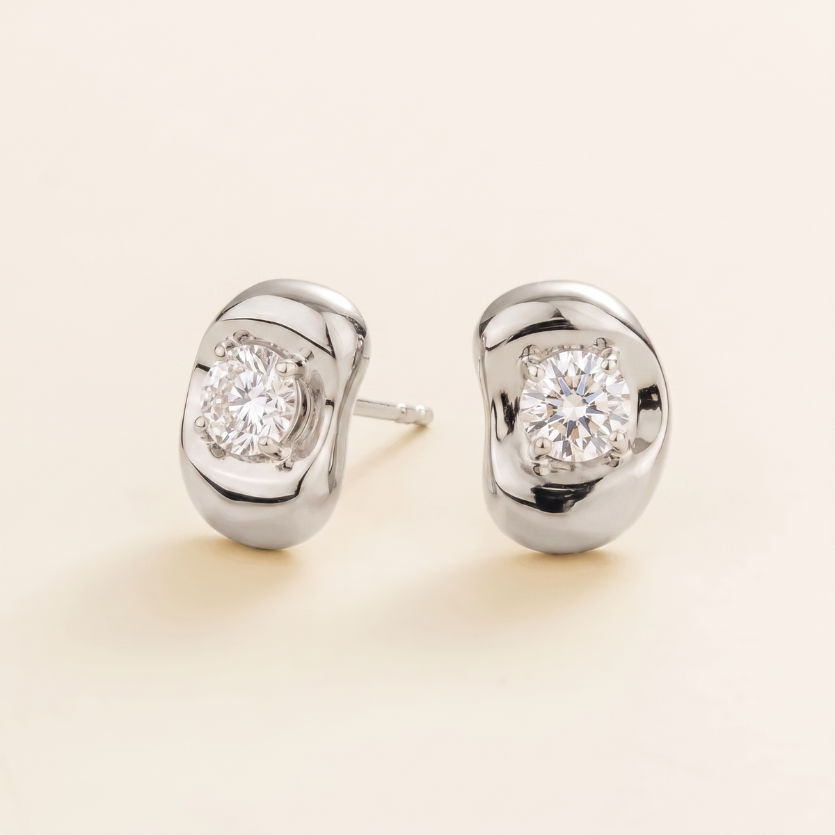 Fava round lab-grown diamond stud earrings in white gold, sculpted pebble setting, angled view | Juvetti London