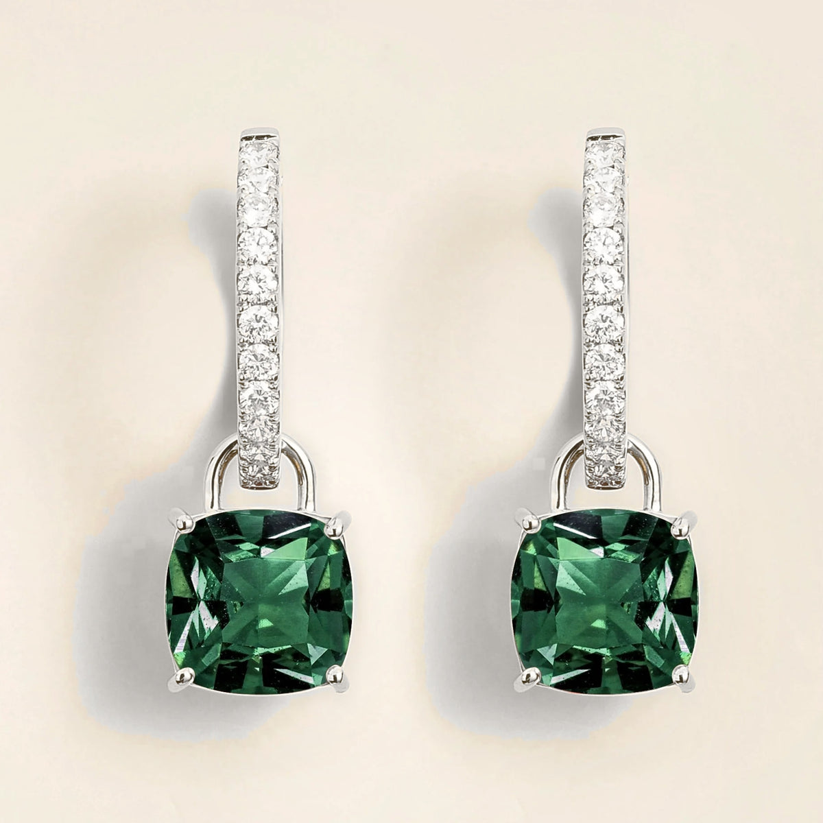 A pair of Roue drop earrings in white gold, featuring cushion cut emeralds and D-F VS grade diamonds.