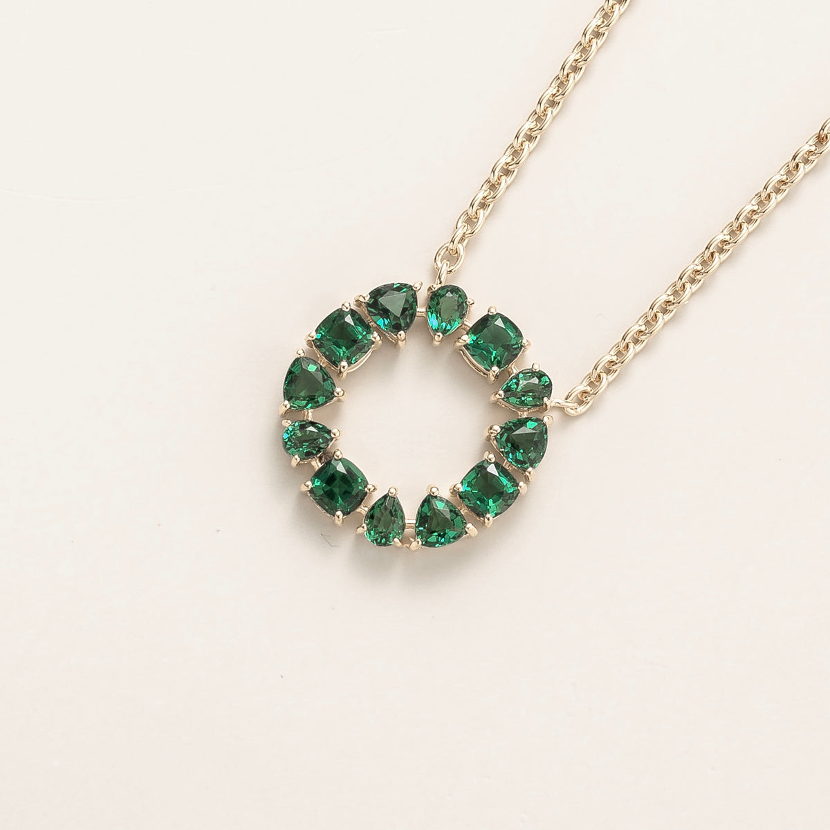 Glorie emerald open circle pendant necklace in white gold, mixed-cut lab-grown emeralds, angled view | Juvetti London