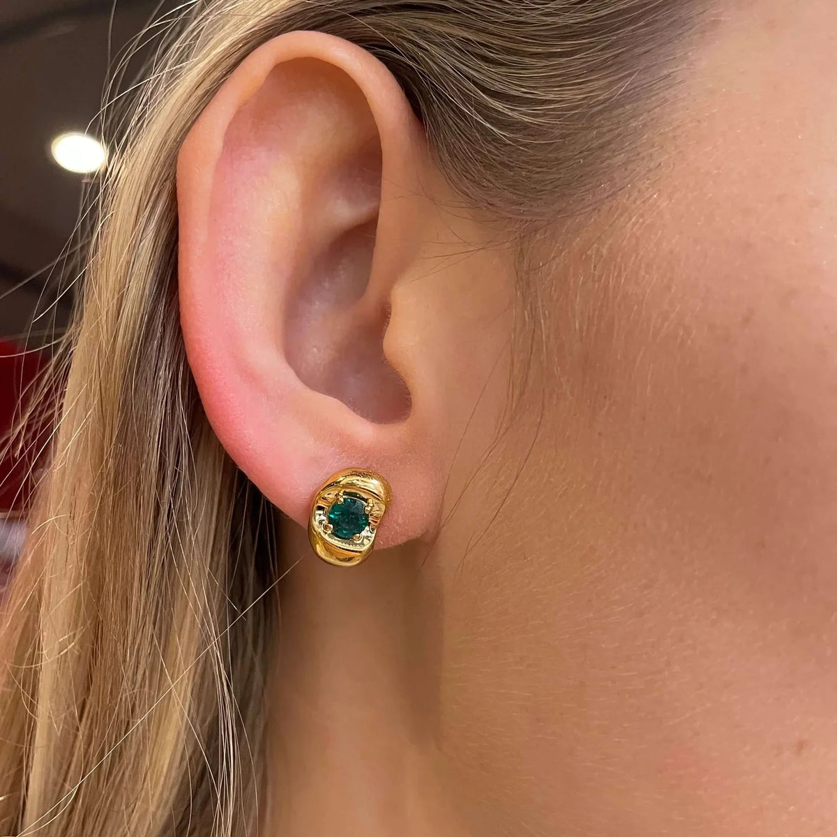 Fava round lab-grown emerald stud earrings in white gold, sculpted pebble setting, worn on the ear | Juvetti London