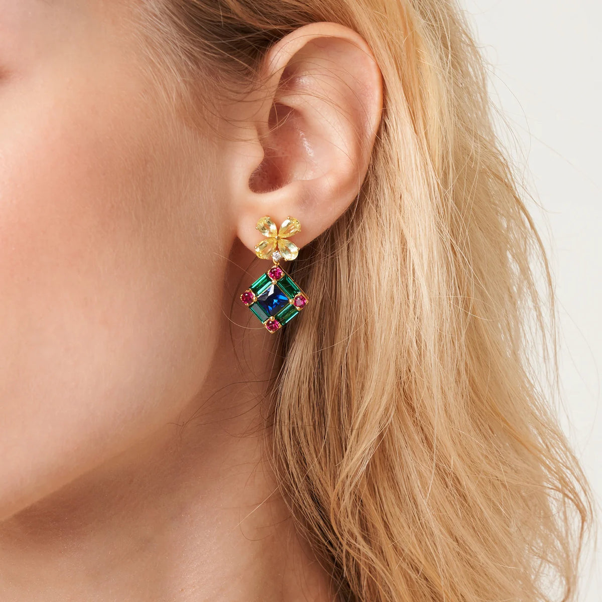 Model wearing Medina floral drop earrings in gold: yellow sapphire, blue sapphire, emerald, ruby and diamond