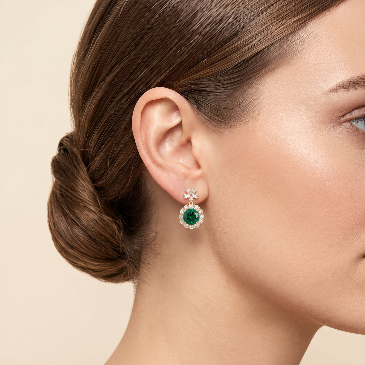 Model wearing Antoinette round emerald & diamond halo flower drop earrings in gold