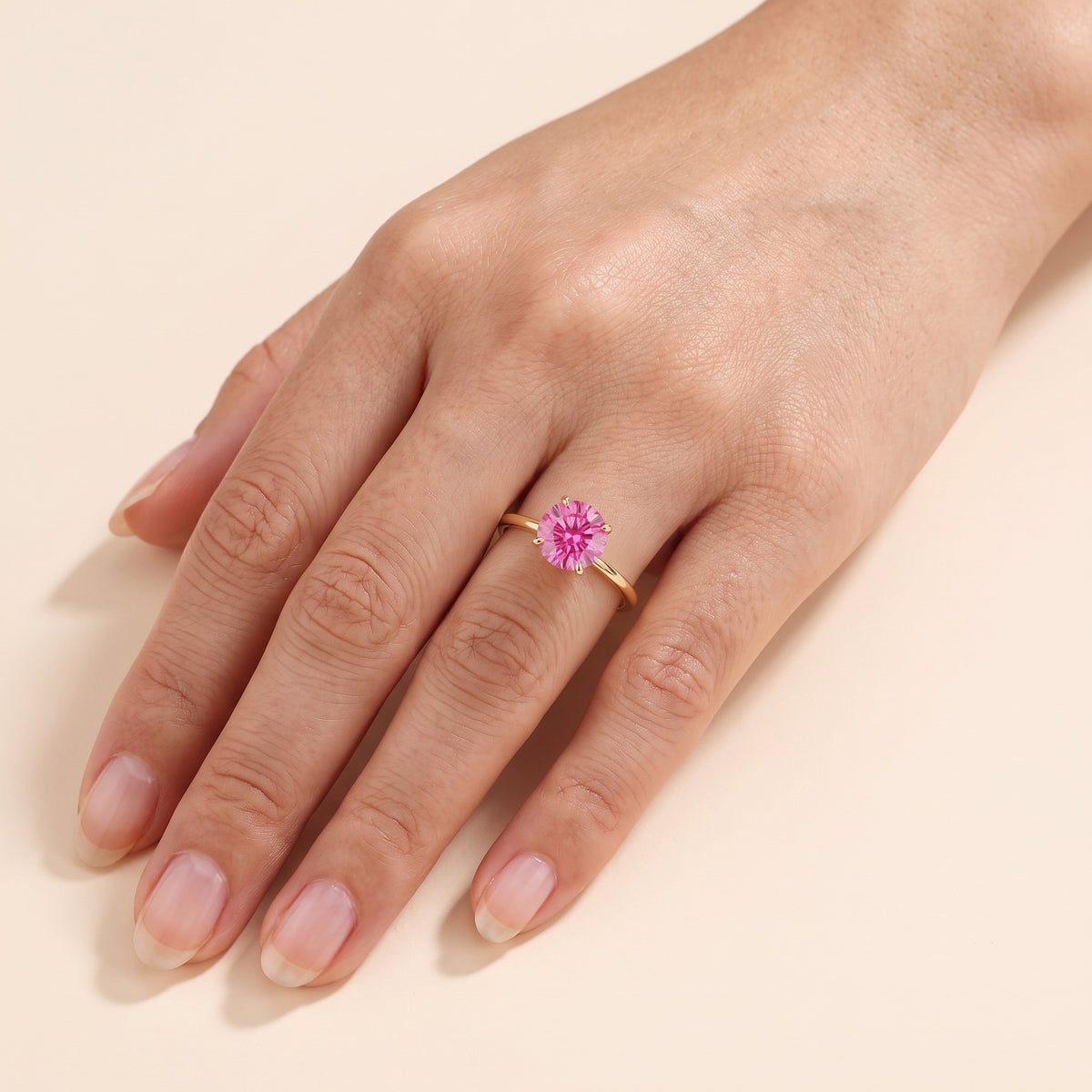 Model wearing the Nina Round Shape Vivid Pink Sapphire Cathedral Solitaire Ring in Gold