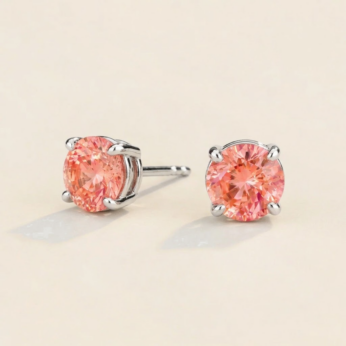 Nina round lab-grown padparadscha sapphire solitaire stud earrings in white gold – angled view | Juvetti London