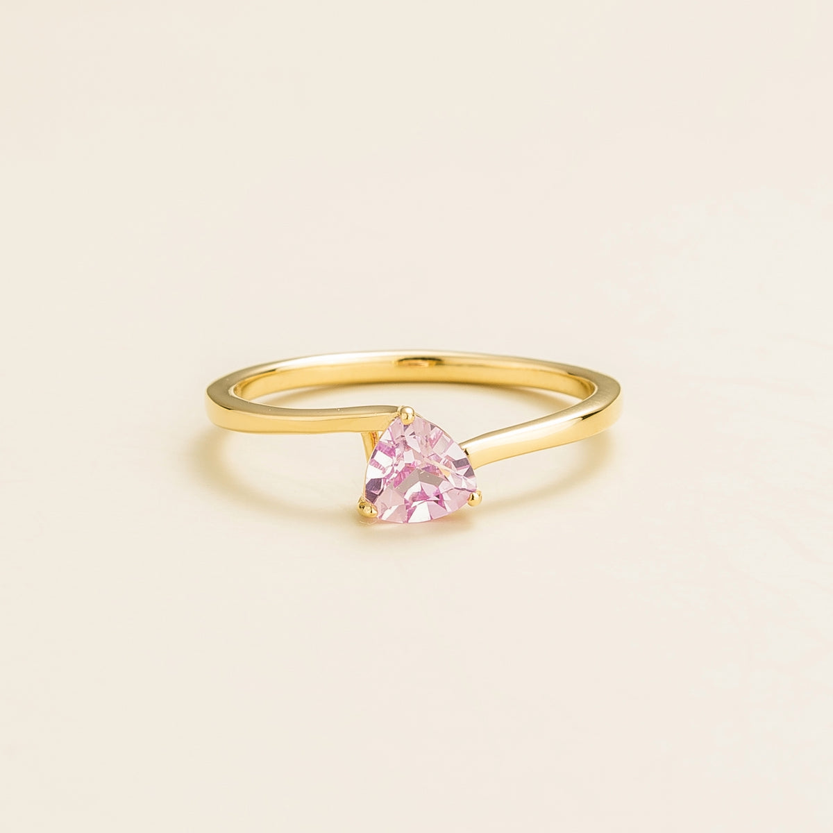 Trillion Pastel Pink Sapphire Solitaire Ring in Gold on beige background