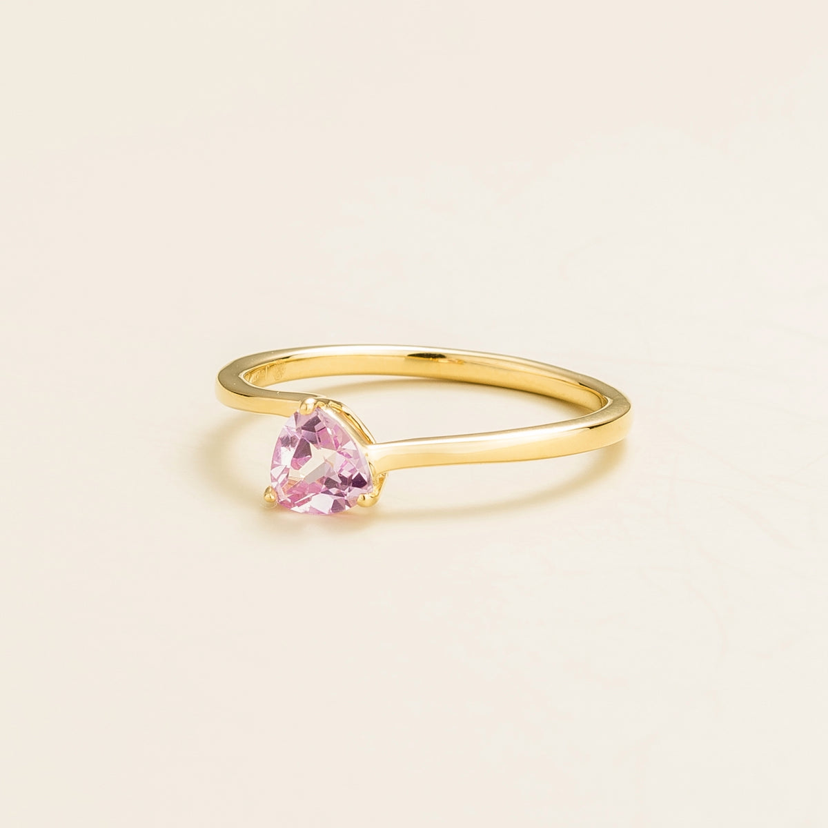 Trillion Pastel Pink Sapphire Solitaire Ring in Gold on beige background