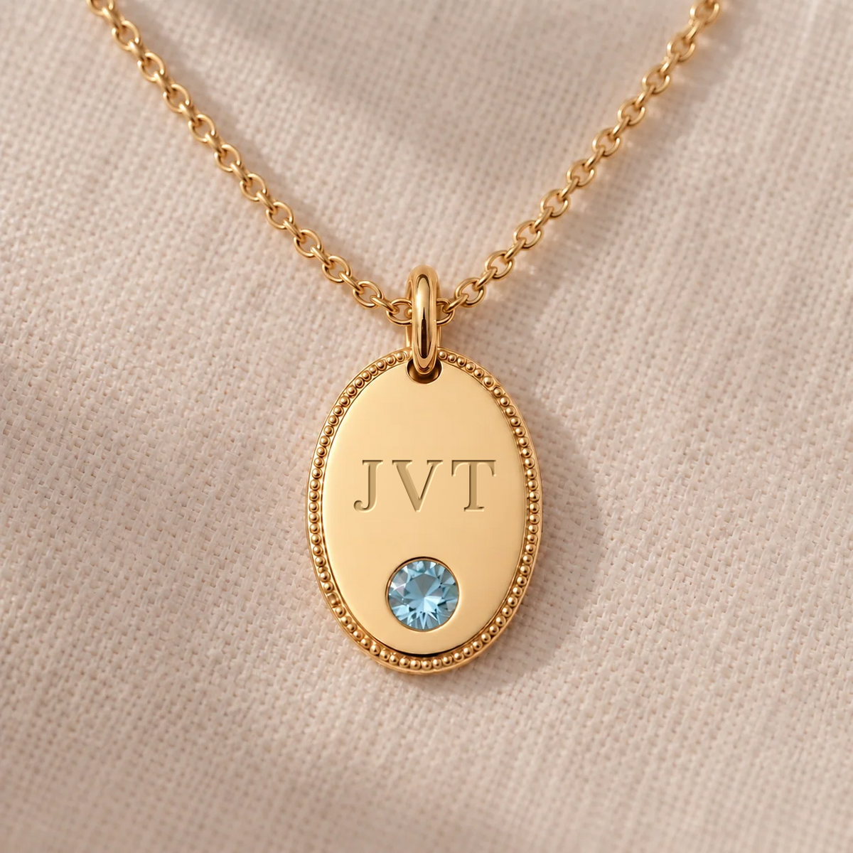 Personalised initial oval pendant necklace in gold, engraved JVT with flush-set aquamarine and milgrain border