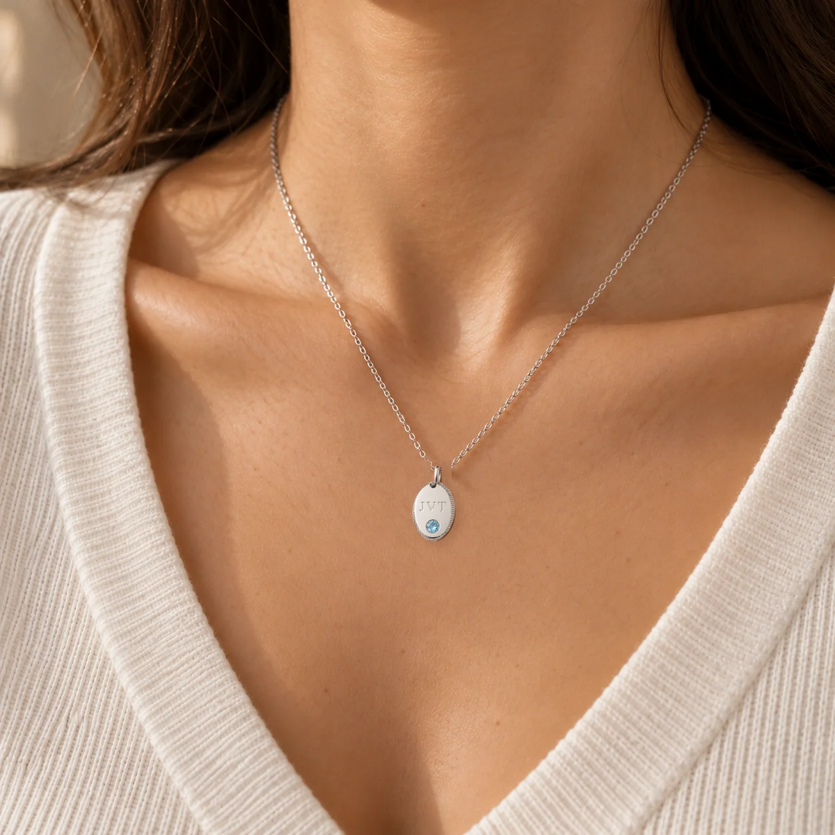 Personalised initial oval pendant necklace in white gold worn on model, shown at true size