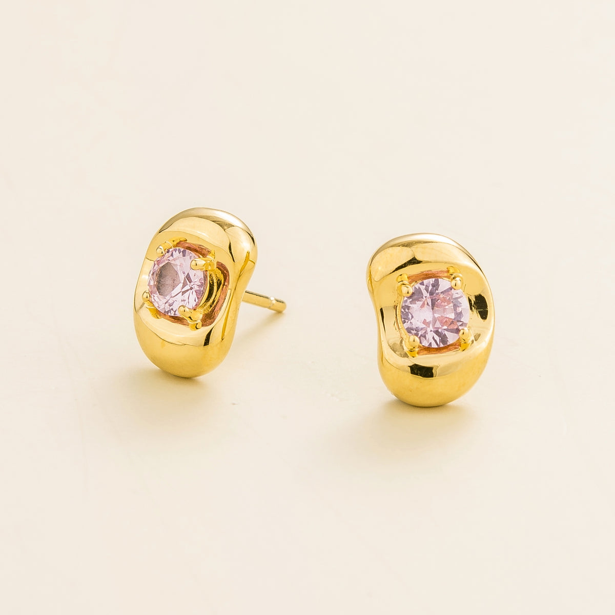 Fava round lab-grown pink sapphire stud earrings in gold, sculpted pebble setting, angled view | Juvetti London