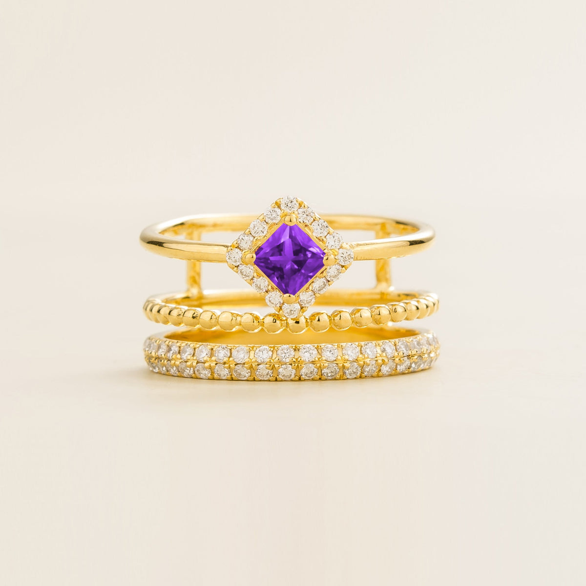 Amici triple-band stacking ring in gold, princess-cut lab-grown purple sapphire in a diamond halo with beaded and pavé bands, front view | Juvetti London