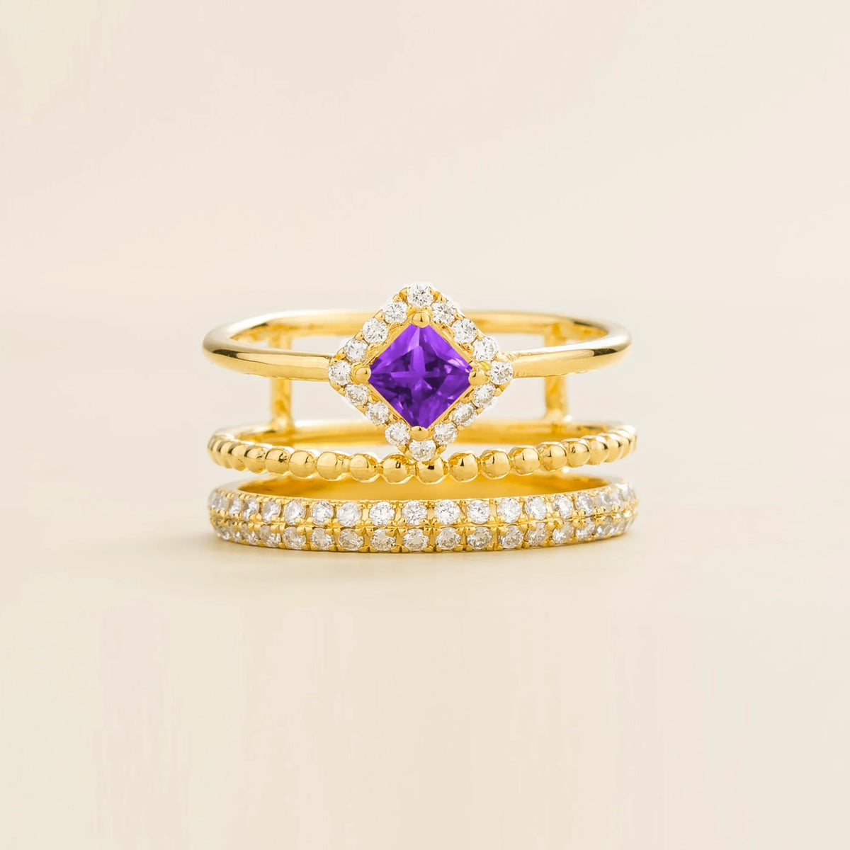 Amici triple-band stacking ring in gold, princess-cut lab-grown purple sapphire in a diamond halo with beaded and pavé bands, front view | Juvetti London
