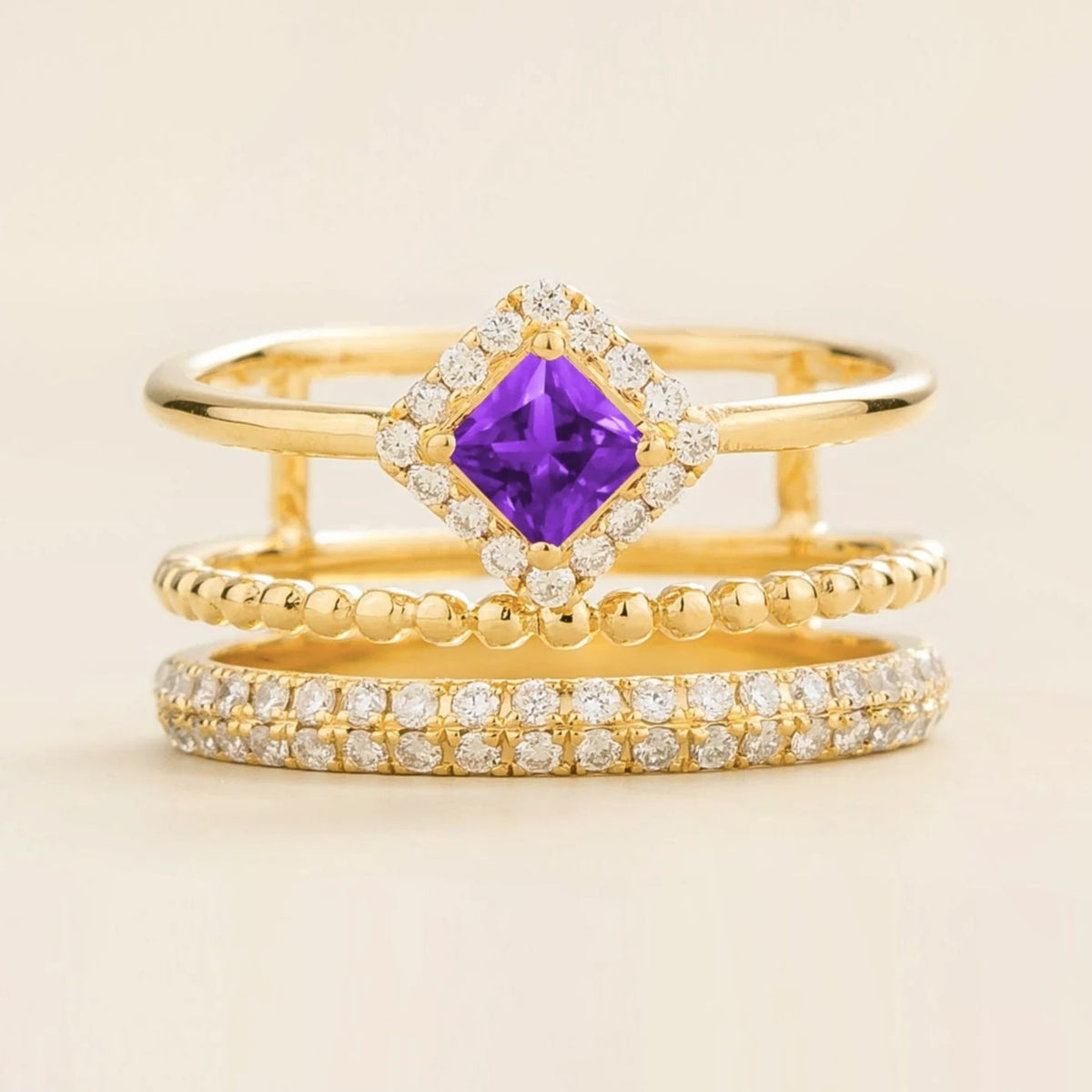 Amici triple-band stacking ring in gold, princess-cut lab-grown purple sapphire in a diamond halo with beaded and pavé bands, front view | Juvetti London