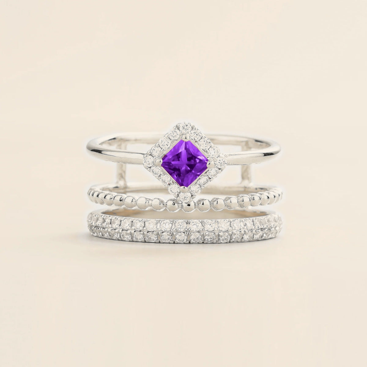 Amici triple-band stacking ring in white gold, princess-cut lab-grown purple sapphire in a diamond halo with beaded and pavé bands, front view | Juvetti London