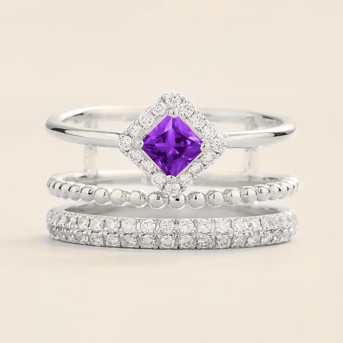 Amici triple-band stacking ring in white gold, princess-cut lab-grown purple sapphire in a diamond halo with beaded and pavé bands, front view | Juvetti London