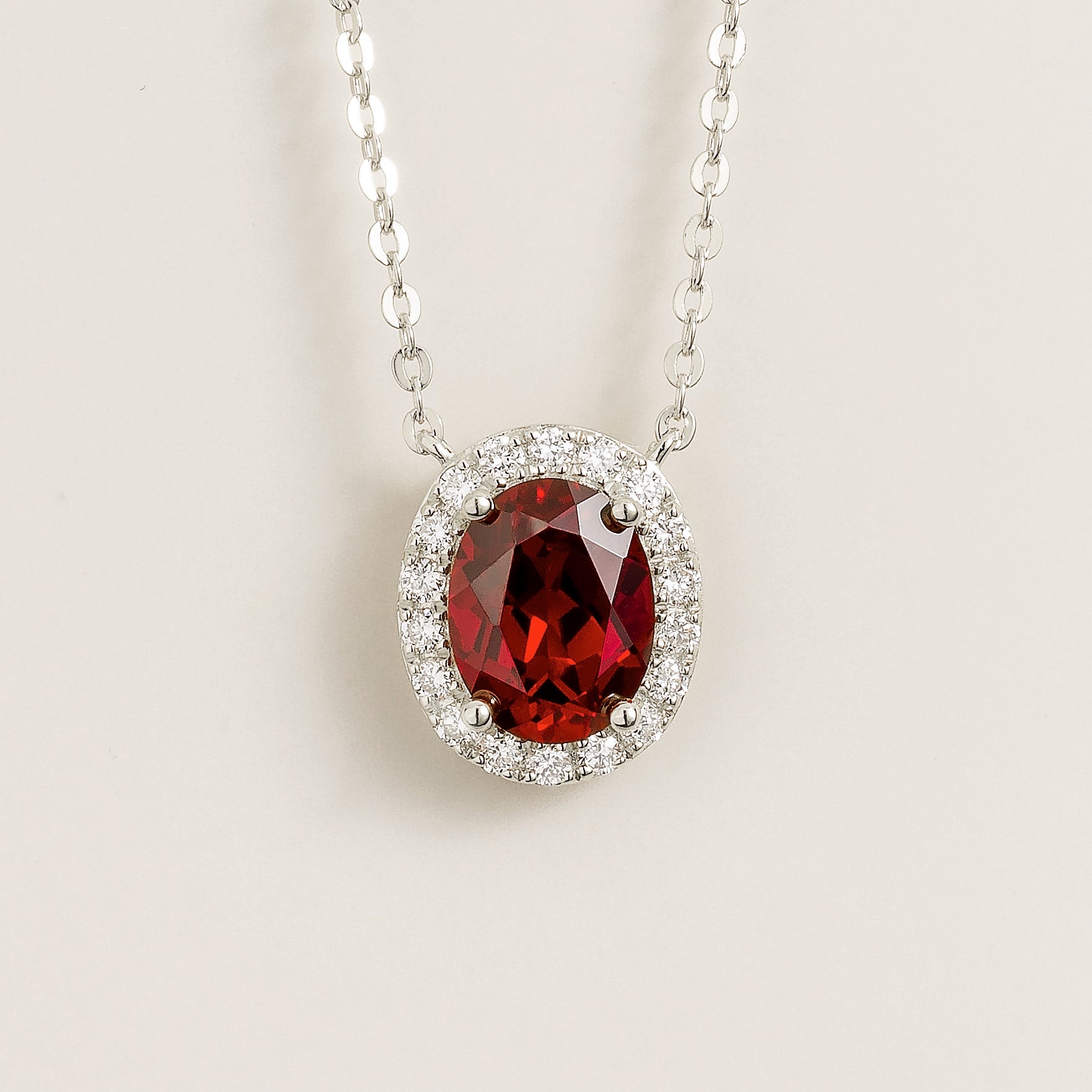 Front view of the Mina Oval Ruby & Diamond Halo Necklace In White Gold, handcrafted by Juvetti London