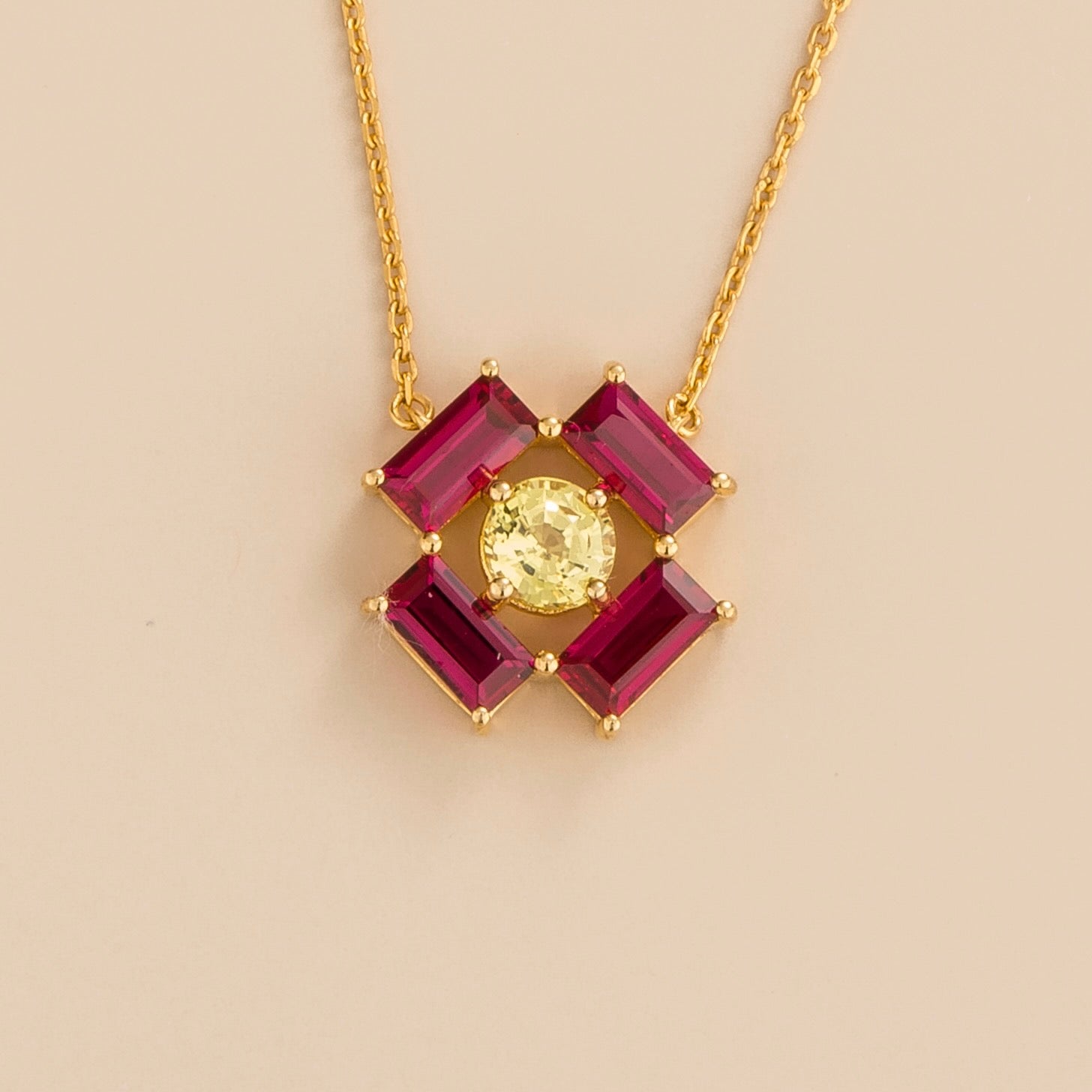 Front view of the Oua Pendant Necklace In Yellow Sapphire & Ruby Set In Gold, handcrafted by Juvetti London