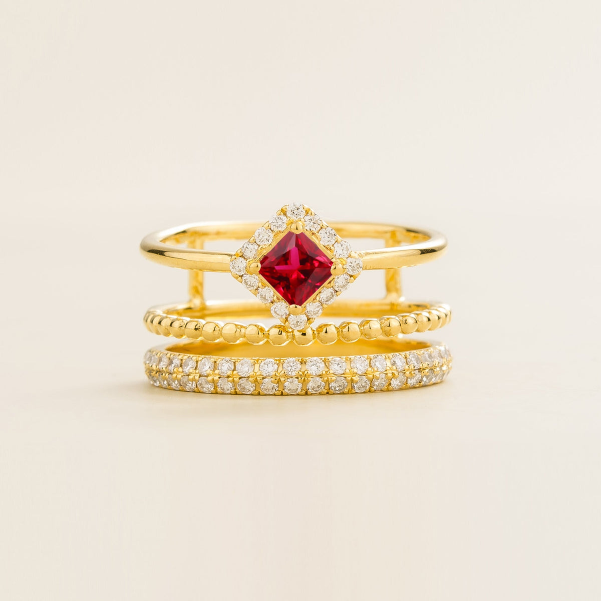 Amici triple-band stacking ring in gold, princess-cut lab-grown ruby in a diamond halo with beaded and pavé bands, front view | Juvetti London