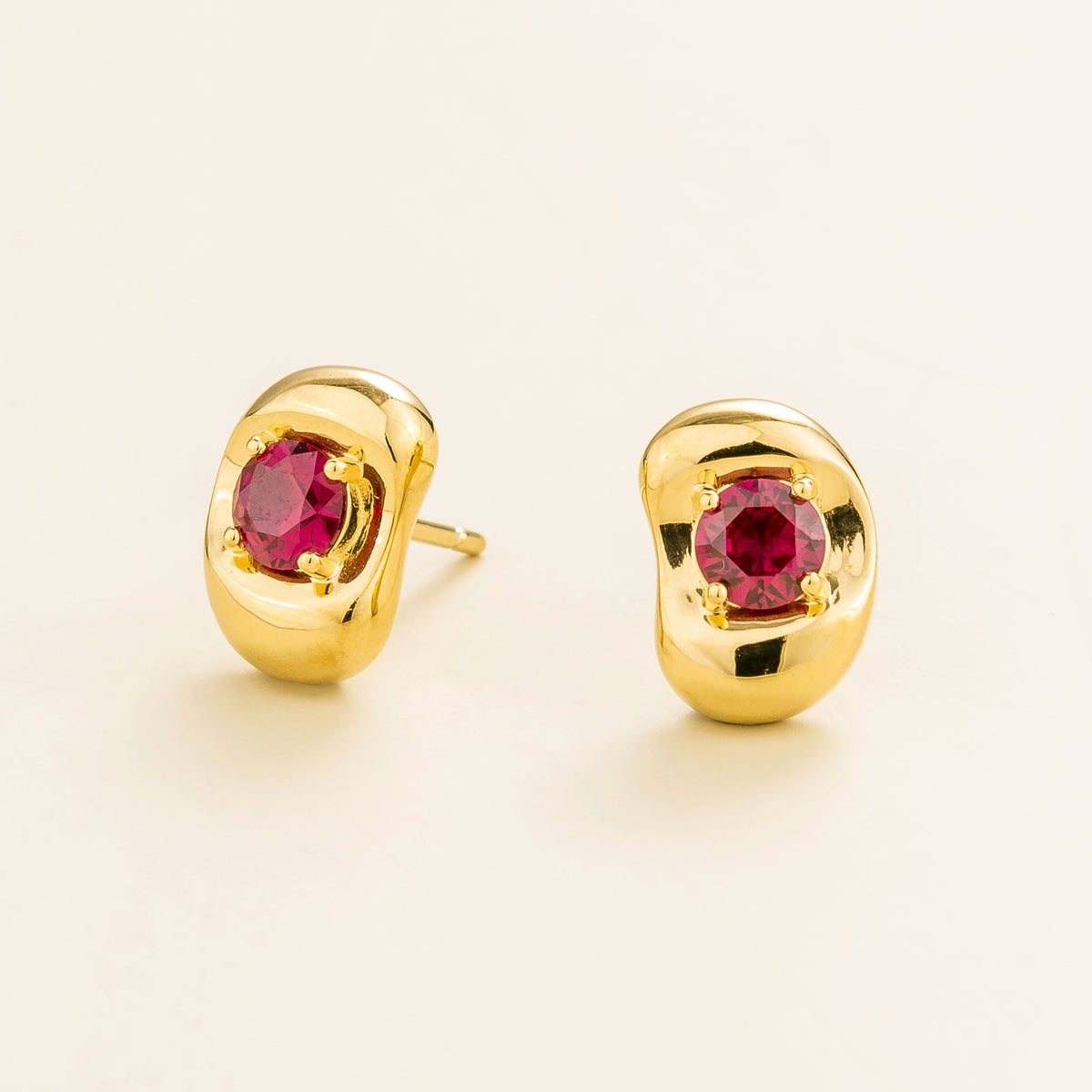 Fava round lab-grown ruby stud earrings in gold, sculpted pebble setting, angled view | Juvetti London