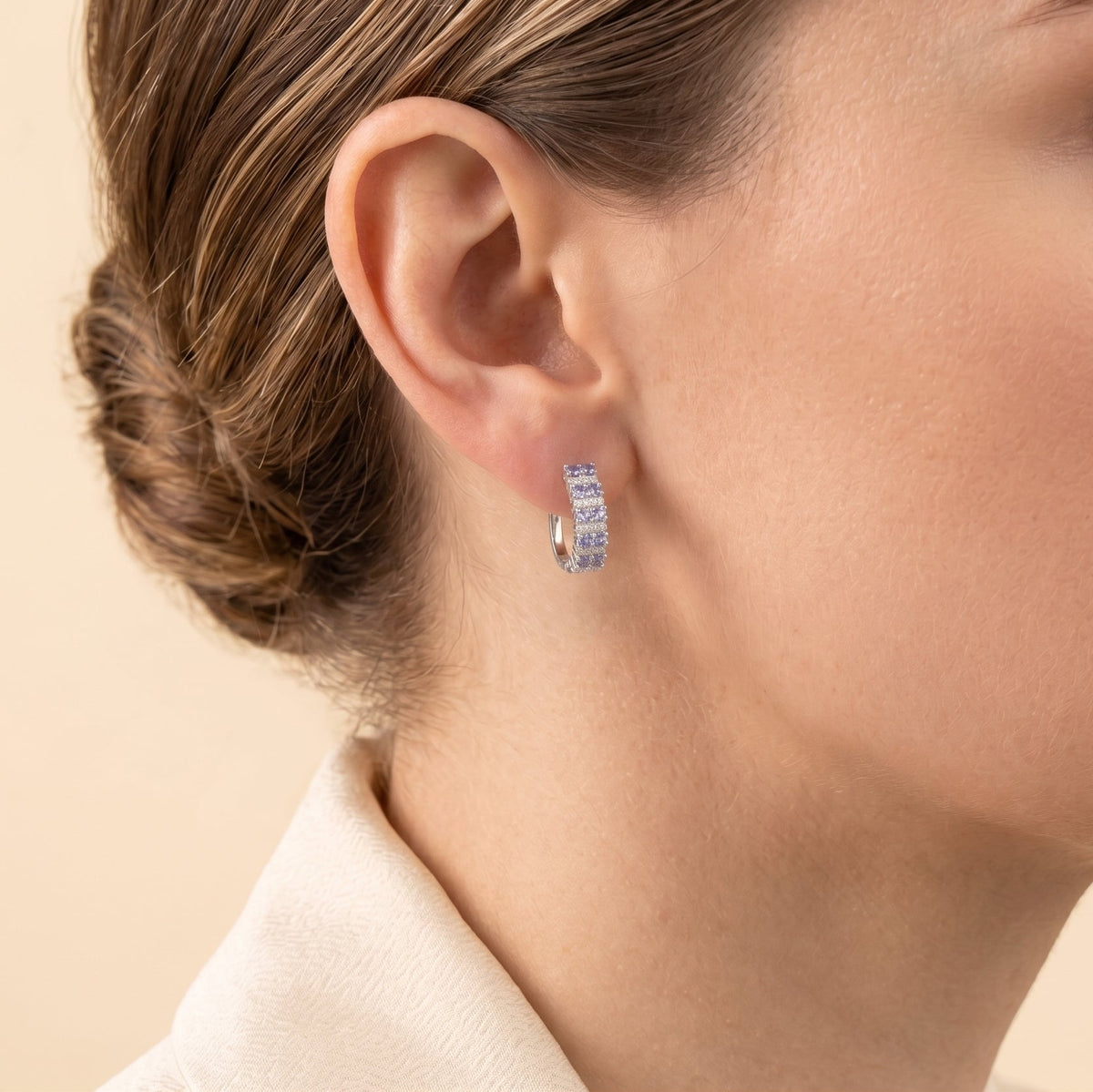Model wearing Tina pastel blue sapphire & diamond huggie hoop earrings in white gold