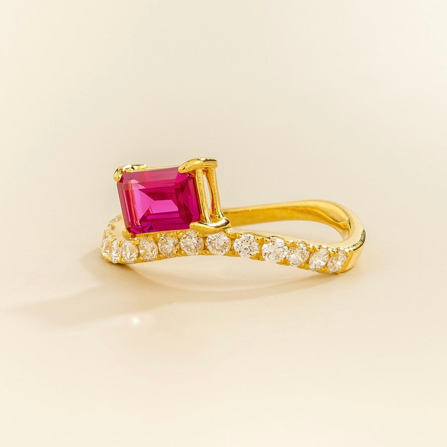 Luno vivid hot pink sapphire emerald-cut ring with diamond pavé in gold, lab-grown sapphire set east-west, angled view | Juvetti London