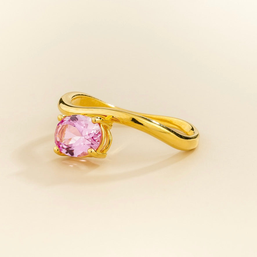 Luno vivid pink sapphire oval ring in gold, lab-grown sapphire set east-west, angled view | Juvetti London