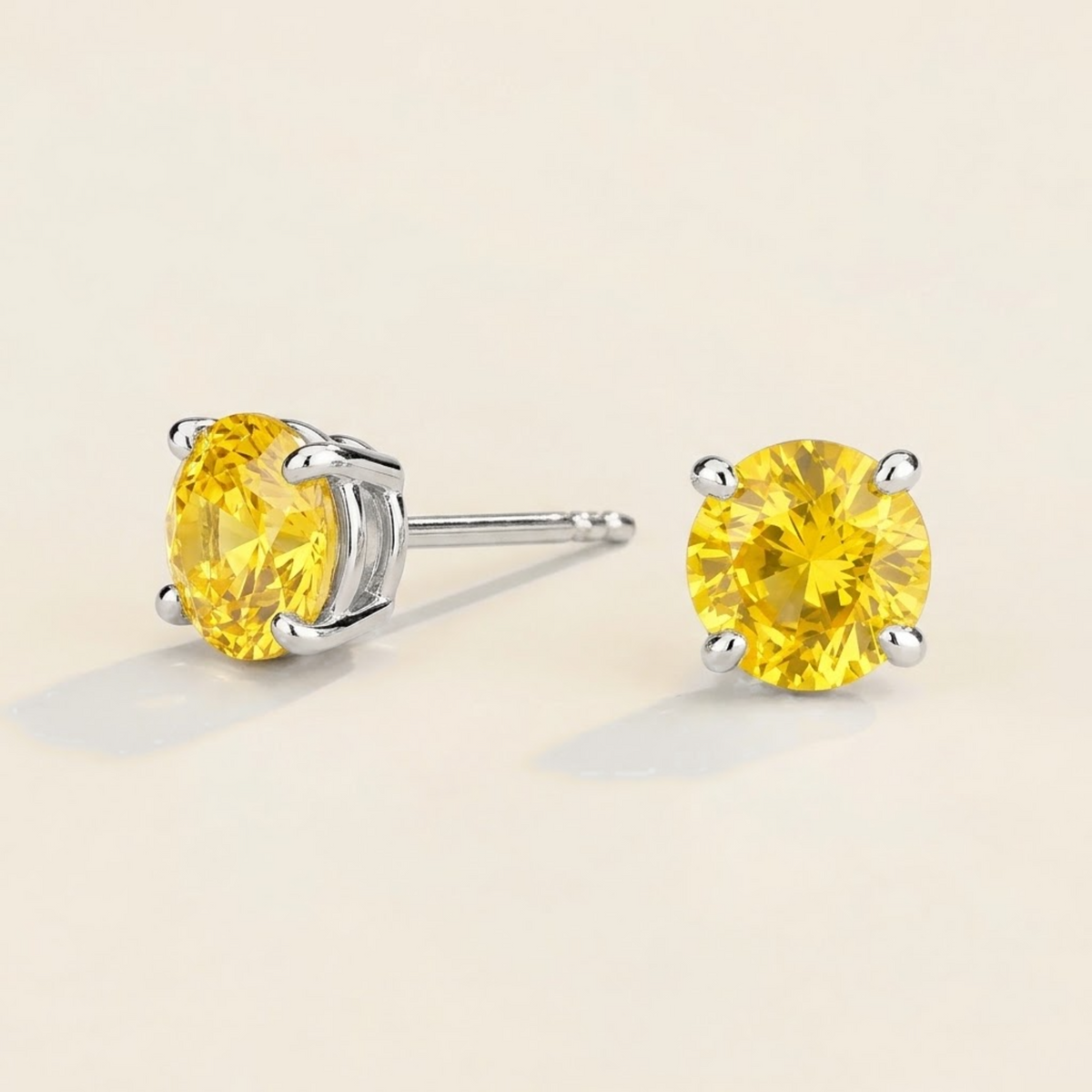 Nina round lab-grown yellow sapphire solitaire stud earrings in white gold – angled view | Juvetti London
