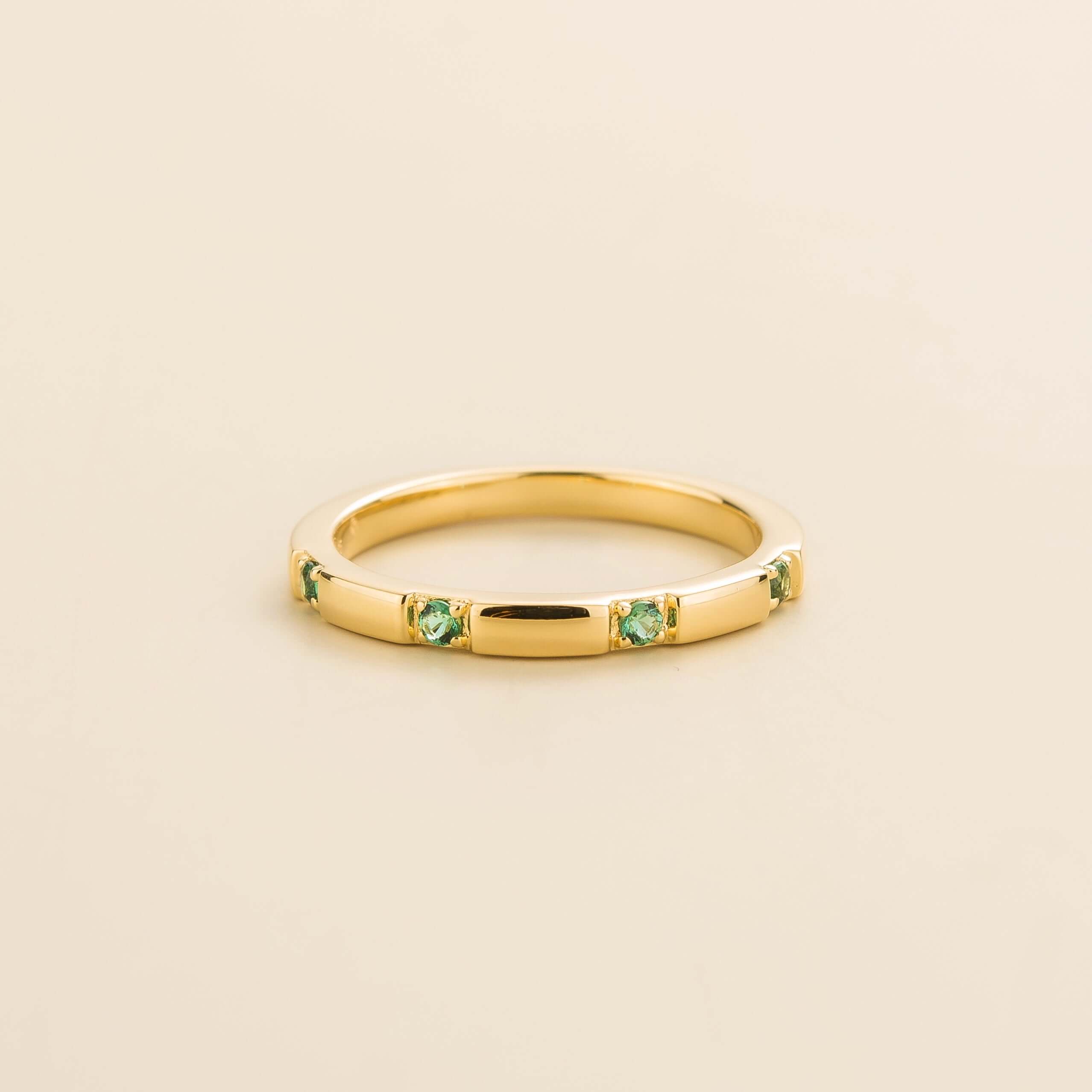 Juvetti yellow gold band set with round lab-grown emerald in a sleek modern design.