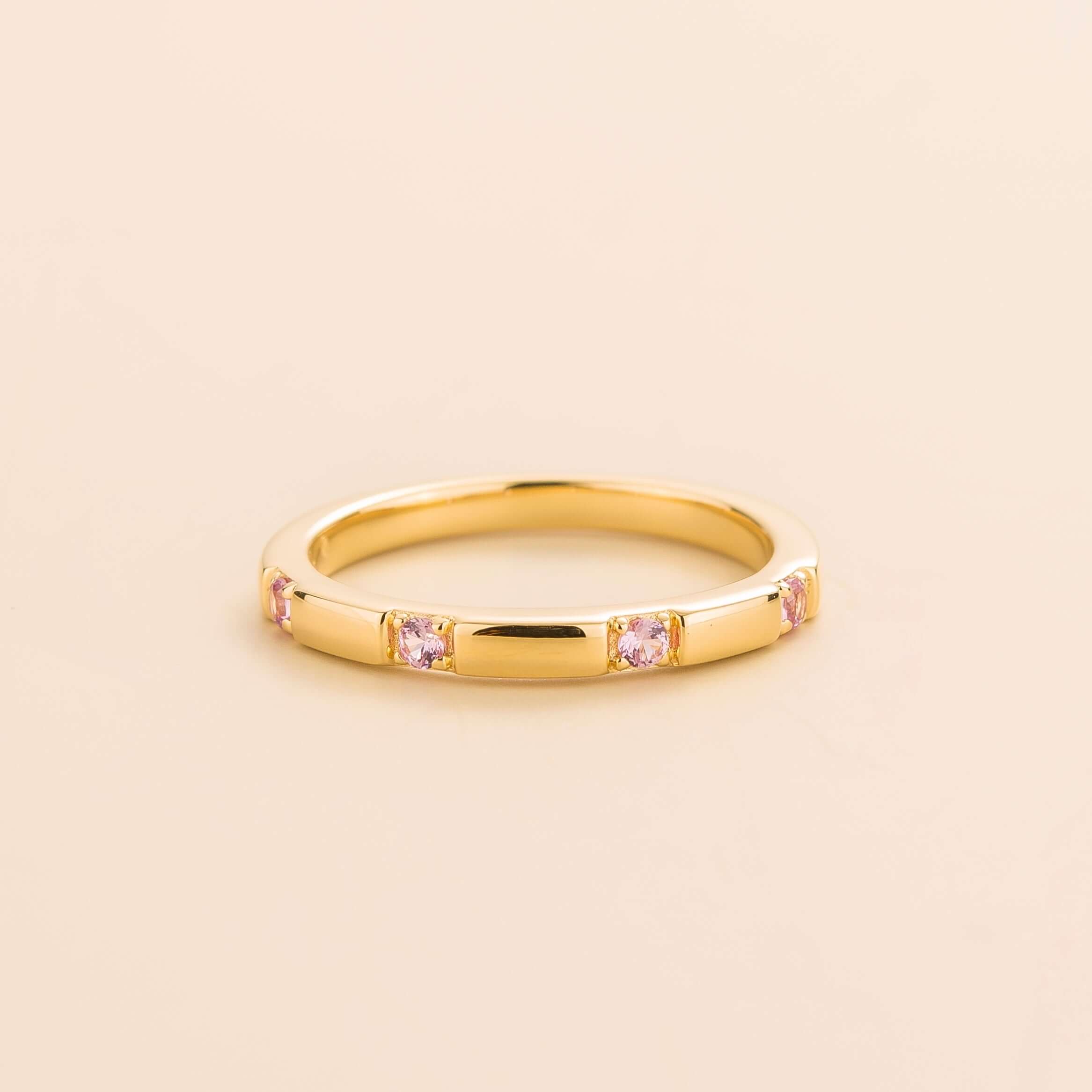 Juvetti yellow gold band set with round lab-grown pink sapphires in a sleek modern design.