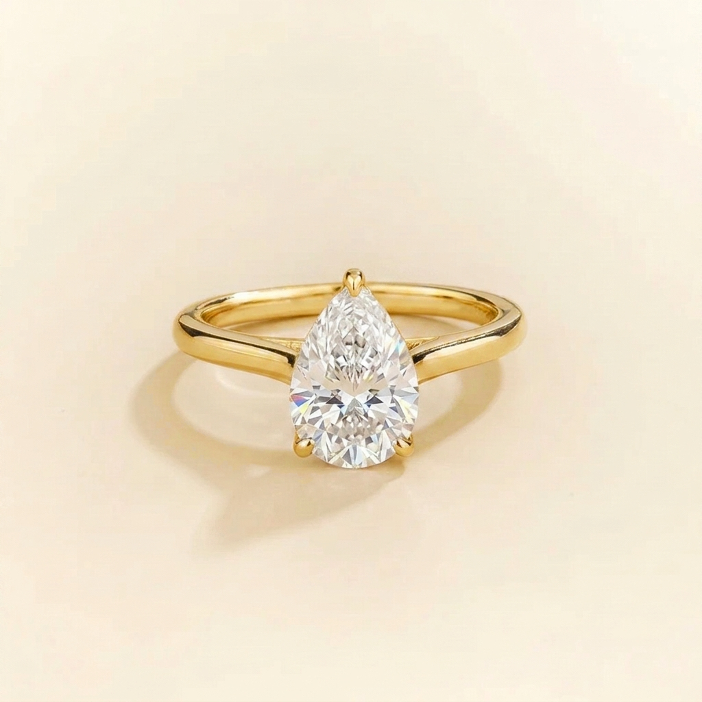 Solitaire engagement ring with a 2 carat pear-cut diamond in a three-prong cathedral setting on a slim polished yellow gold band.