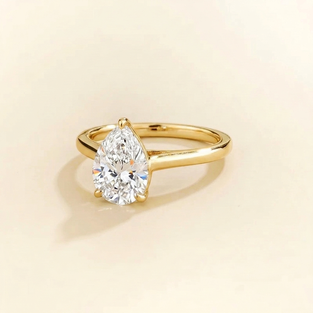 Solitaire engagement ring with a 2 carat pear-cut diamond in a three-prong cathedral setting on a slim polished yellow gold band.